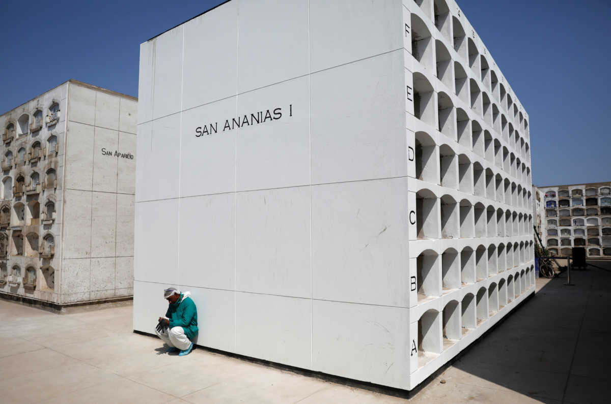 A funeral worker crouches while waiting for coffins to arrive for their burials, amidst the outbreak of the coronavirus disease (COVID-19), at the cemetery in Lima, Peru May 9, 2020.  REUTERS