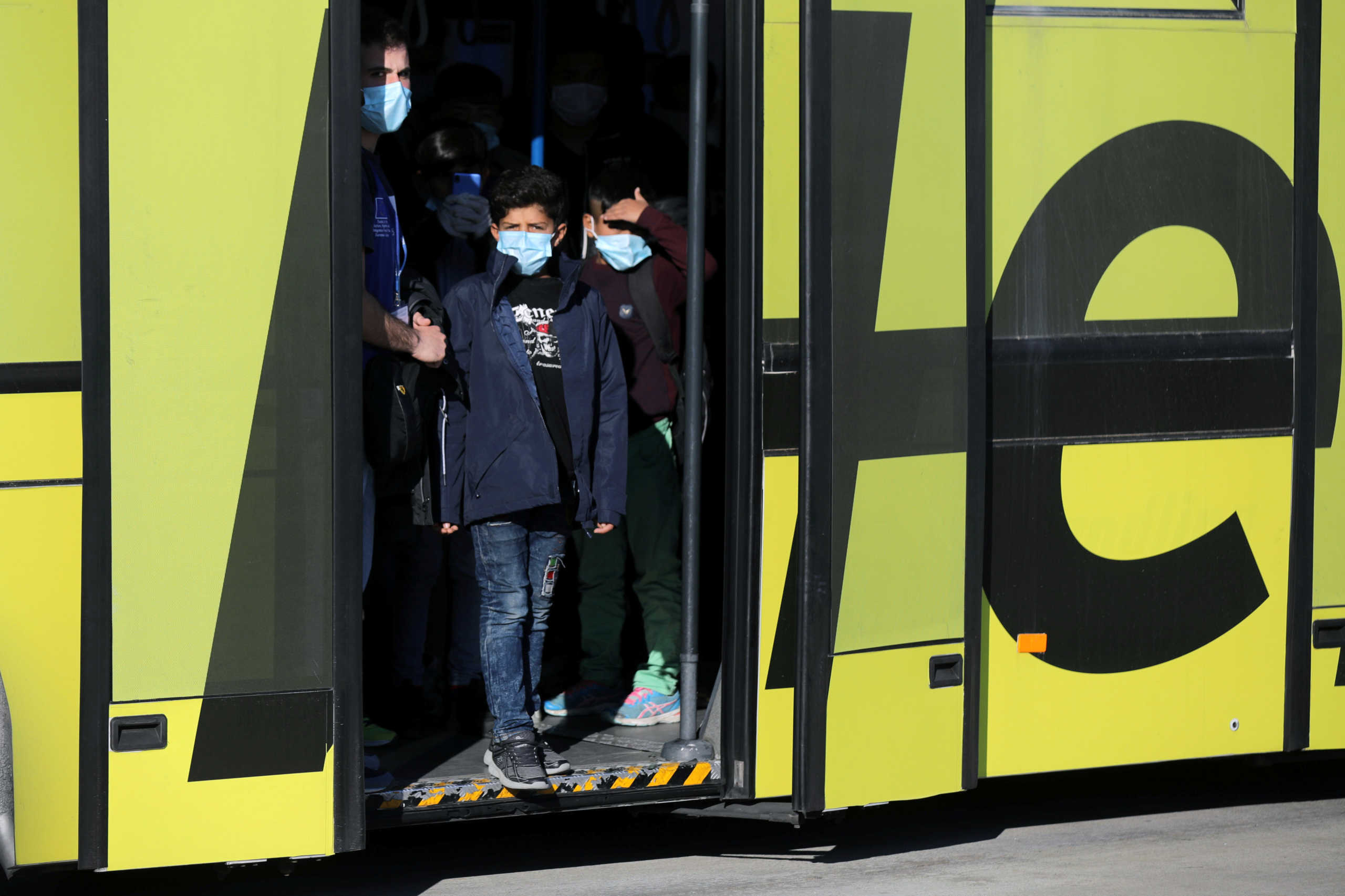 Unaccompanied children from overcrowded migrant camps who will be transferred to Germany, wear protective face masks as a precaution against the spread of coronavirus disease (COVID-19) as they arrive to board a plane at the Athens International Airport, Greece, April 18, 2020. REUTERS