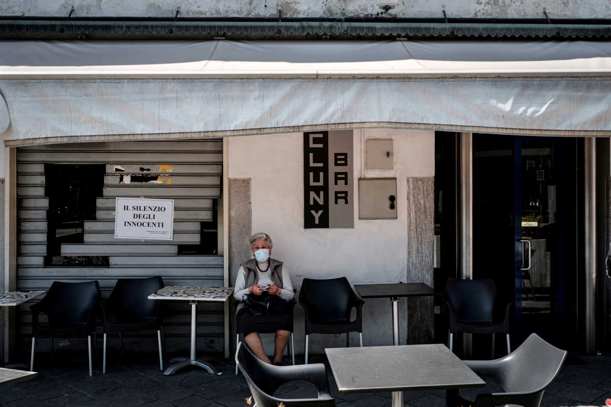Life in Italy's original 'red zones': A woman wearing a mask sits outside a bar that has reopened offering takeways in Codogno, the small northern town where Italy's first patient was diagnosed with the coronavirus disease (COVID-19) on February 21, as the country begins a staged end to a nationwide lockdown, in this picture taken by schoolteacher Marzio Toniolo, May 4, 2020. Codogno residents had been on lockdown for over 10 weeks, as they were part of a small cluster of northern towns where cases and deaths immediately surged after the first patient was diagnosed. Picture taken May 4, 2020. Marzio Toniolo via REUTERS THIS IMAGE HAS BEEN SUPPLIED BY A THIRD PARTY. MANDATORY CREDIT