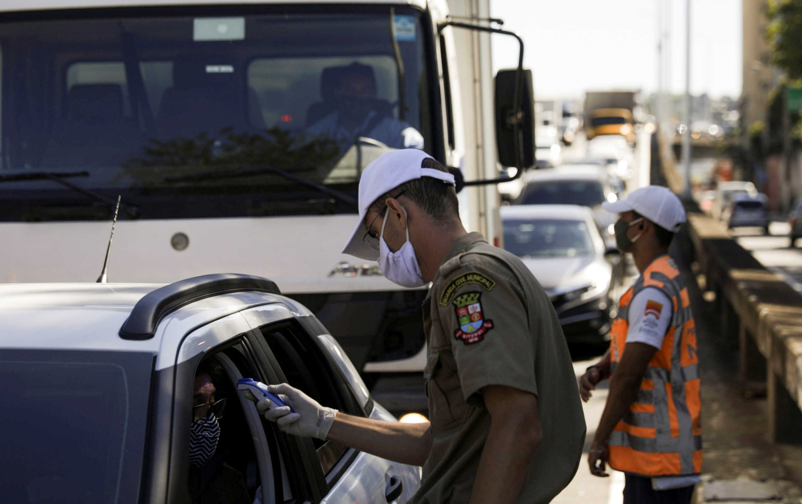 An agent checks the temperature of a driver at the entrance of Niteroi city during its first day of lockdown, as the spread of the coronavirus disease (COVID-19) continues, near Rio de Janeiro, Brazil, May 11, 2020. REUTERS