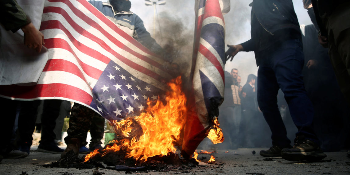 Demonstrators burn the U.S. and British flags during a protest against the assassination of the Iranian Major-General Qassem Soleimani, head of the elite Quds Force, and Iraqi militia commander Abu Mahdi al-Muhandis who were killed in an air strike in Baghdad airport, in Tehran, Iran January 3, 2020. WANA (West Asia News Agency)