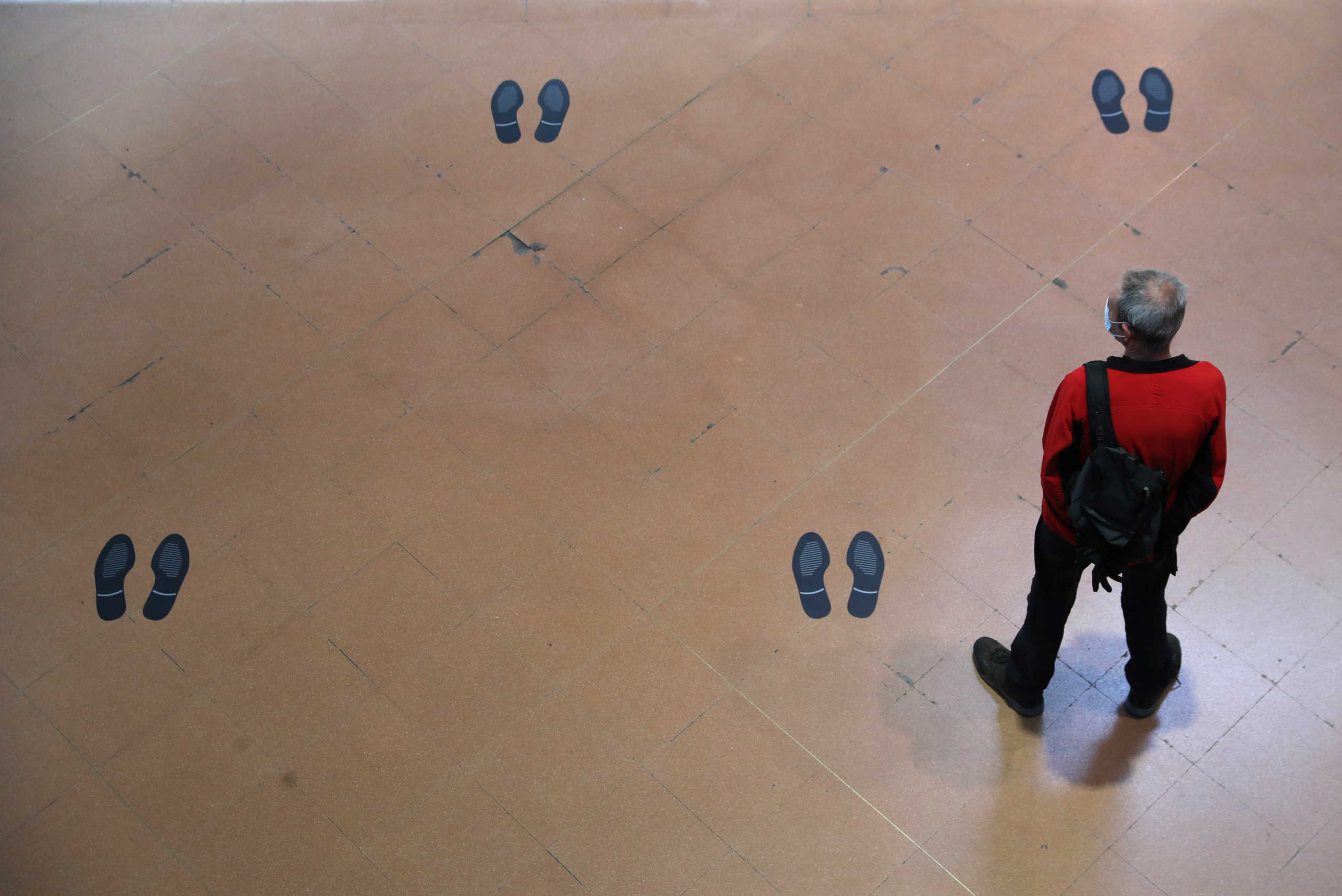 A commuter wearing a protective mask stands amid marks for social distancing on the floor of the Atocha train station, on the first day mask usage is mandatory in public transport, amid the coronavirus disease (COVID-19) outbreak in Madrid, Spain, May 4, 2020. REUTERS