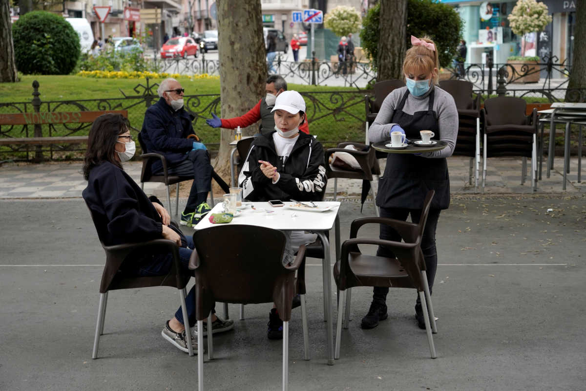 A waitress wearing a protective face mask and gloves serves customers as some Spanish provinces are allowed to ease restrictions during the phase one amid the coronavirus disease (COVID-19) outbreak, in Cuenca, Spain May 11, 2020. REUTERS