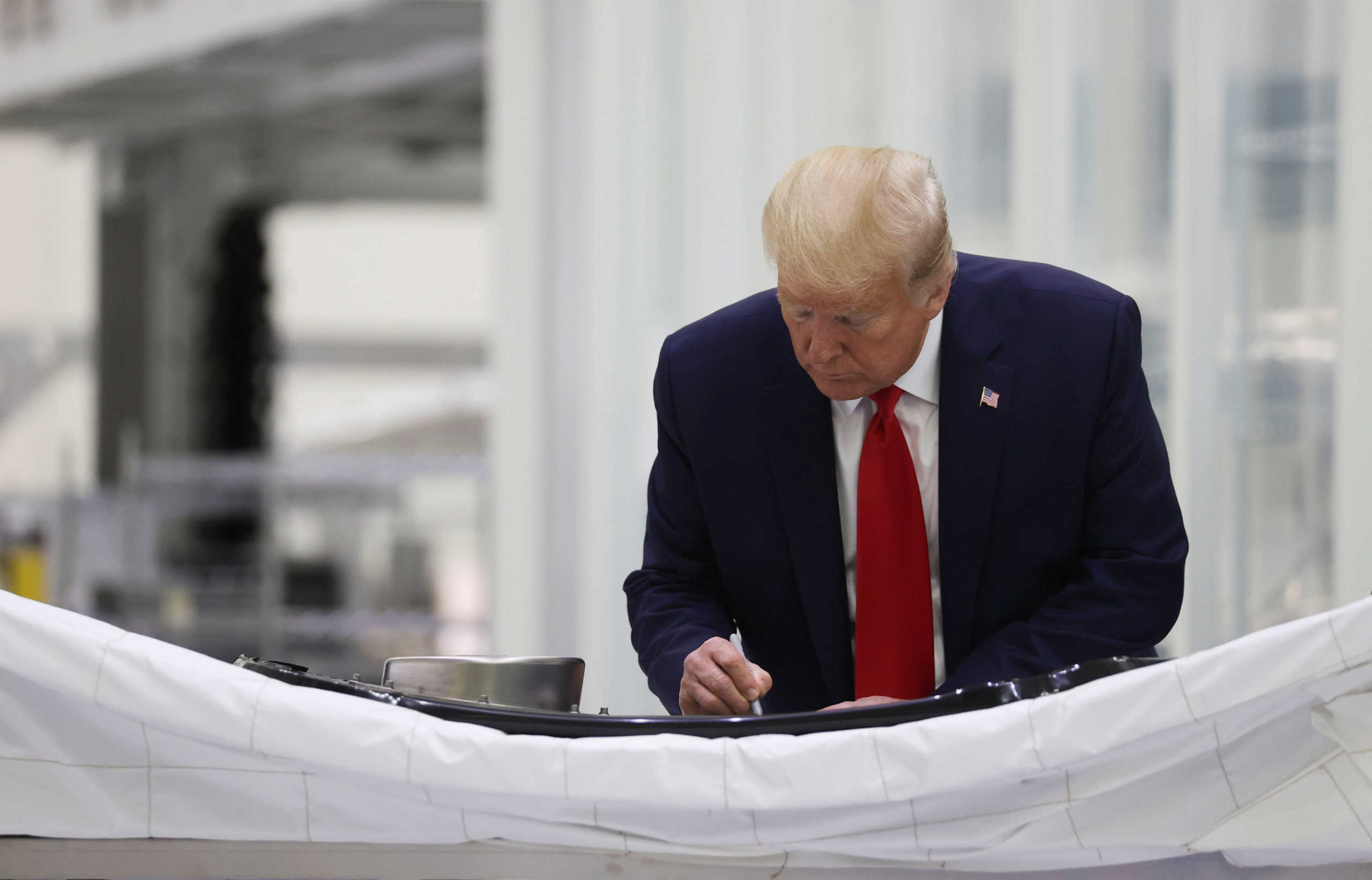 U.S. President Donald Trump signs his name as he tours the Neil Armstrong Operations and Checkout Facility at the Kennedy Space Center in Cape Canaveral, Florida, U.S., May 27, 2020. REUTERS