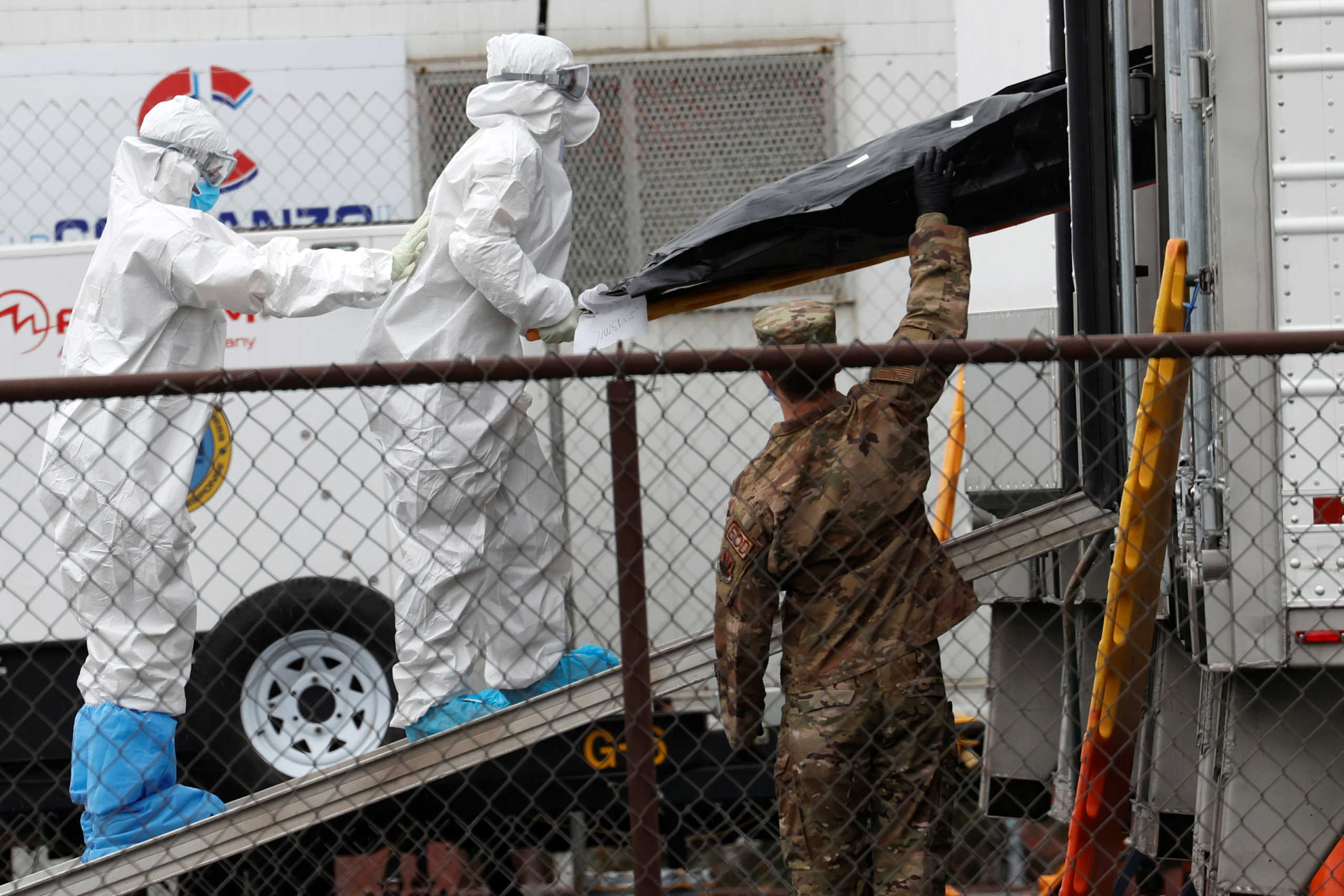 Workers wearing personal protective equipment (PPE) move the body of a deceased person from a refrigerated truck trailer set up at a temporary morgue outside University Hospital during the outbreak of the coronavirus disease (COVID-19) in Newark, New Jersey, U.S., May 6, 2020. Picture taken May 6, 2020. REUTERS