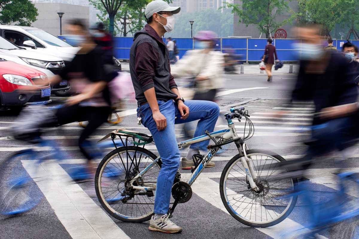 People wearing protective face masks ride bicycles on a street in Wuhan, the Chinese city hit the hardest by the coronavirus disease (COVID-19) outbreak, in the Hubei province, China, May 14, 2020. REUTERS