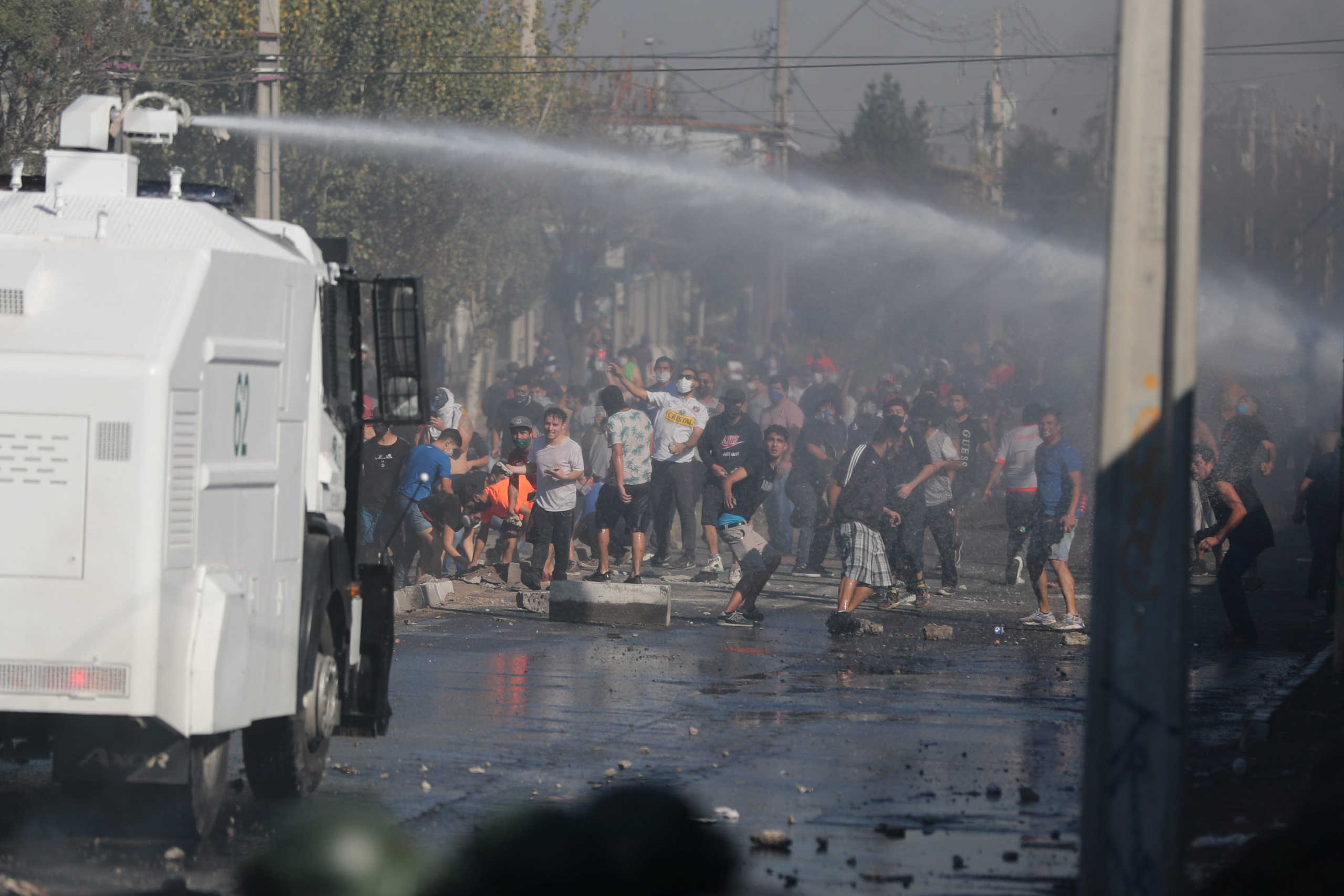 People from a poor neighborhood clash with riot police while protesting against the lack of help from the government during a general quarantine imposed due to a surge of fresh coronavirus disease (COVID-19) cases, at 'El Bosque' area in Santiago, Chile May 18, 2020. REUTERS