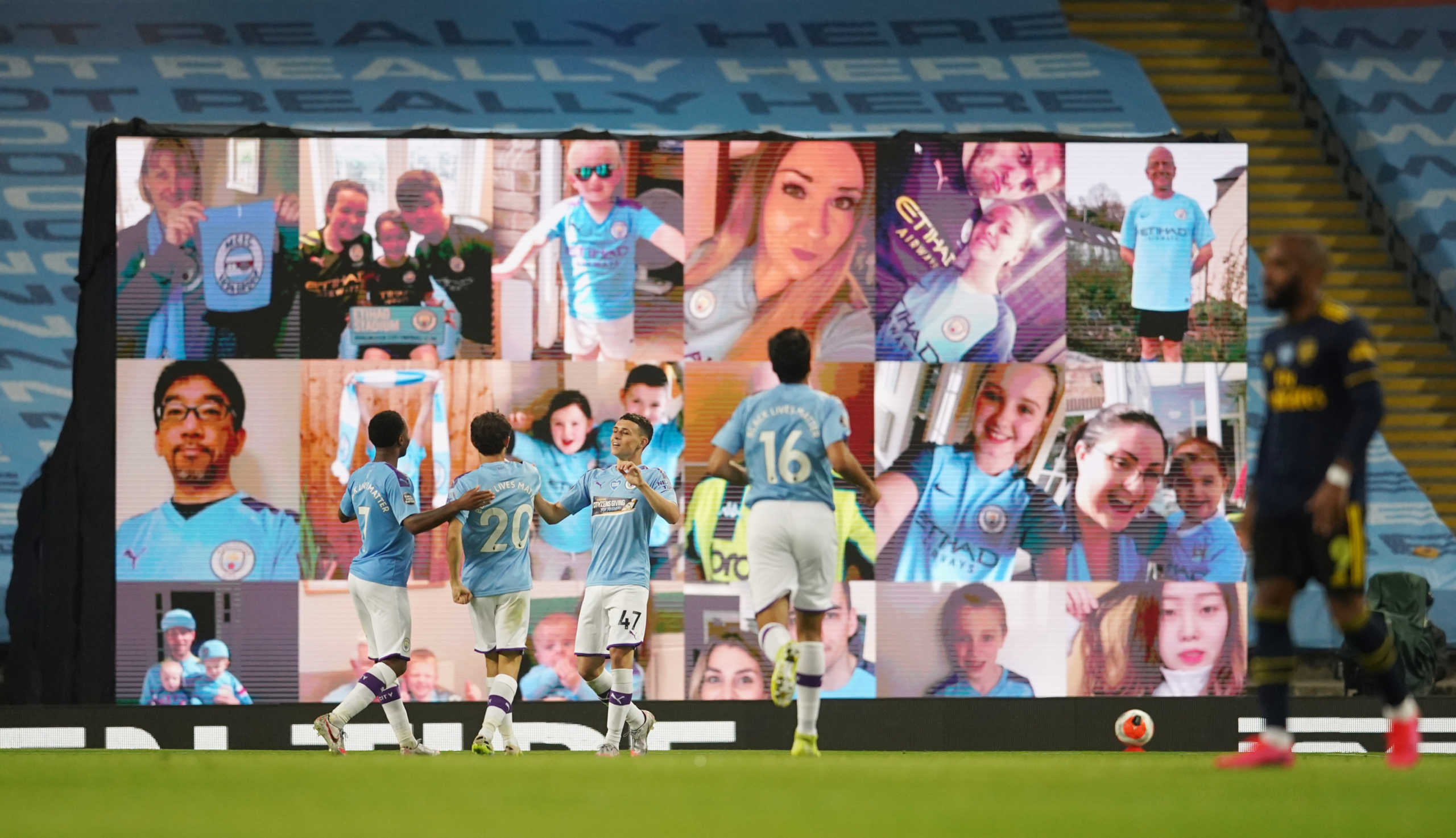 Soccer Football - Premier League - Manchester City v Arsenal - Etihad Stadium, Manchester, Britain - June 17, 2020 Manchester City's Phil Foden celebrates scoring their third goal with teammates in front of a big screen displaying fans as play resumes behind closed doors following the outbreak of the coronavirus disease (COVID-19) Dave Thompson