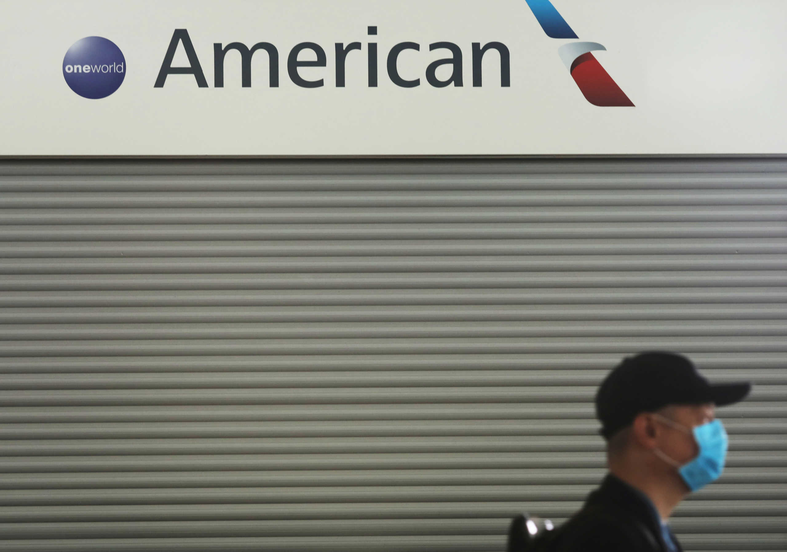 FILE PHOTO: Passenger wears a protective face mask as he walks past the American Airlines ticketing desk at Josep Tarradellas Barcelona-El Prat Airport, after further cases of coronavirus were confirmed in Barcelona, Spain March 12, 2020. REUTERS