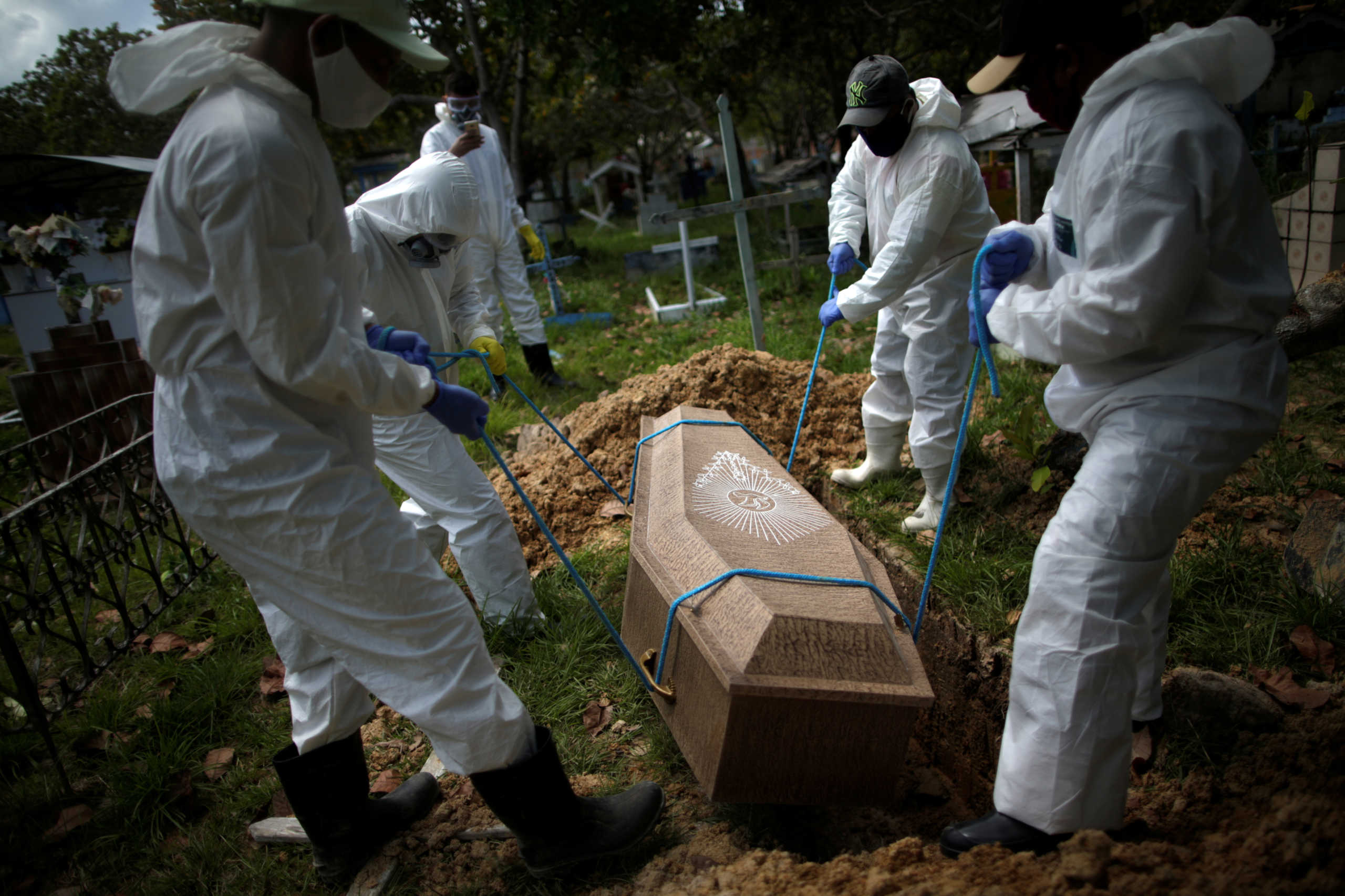 Gravediggers wearing protective suits bury the coffin of 70-year-old Manuel Farias, who died from the coronavirus disease (COVID-19), at Recanto da Paz cemetery, in Breves, southwest of Marajo island in Para state, Brazil, June 7, 2020. REUTERS