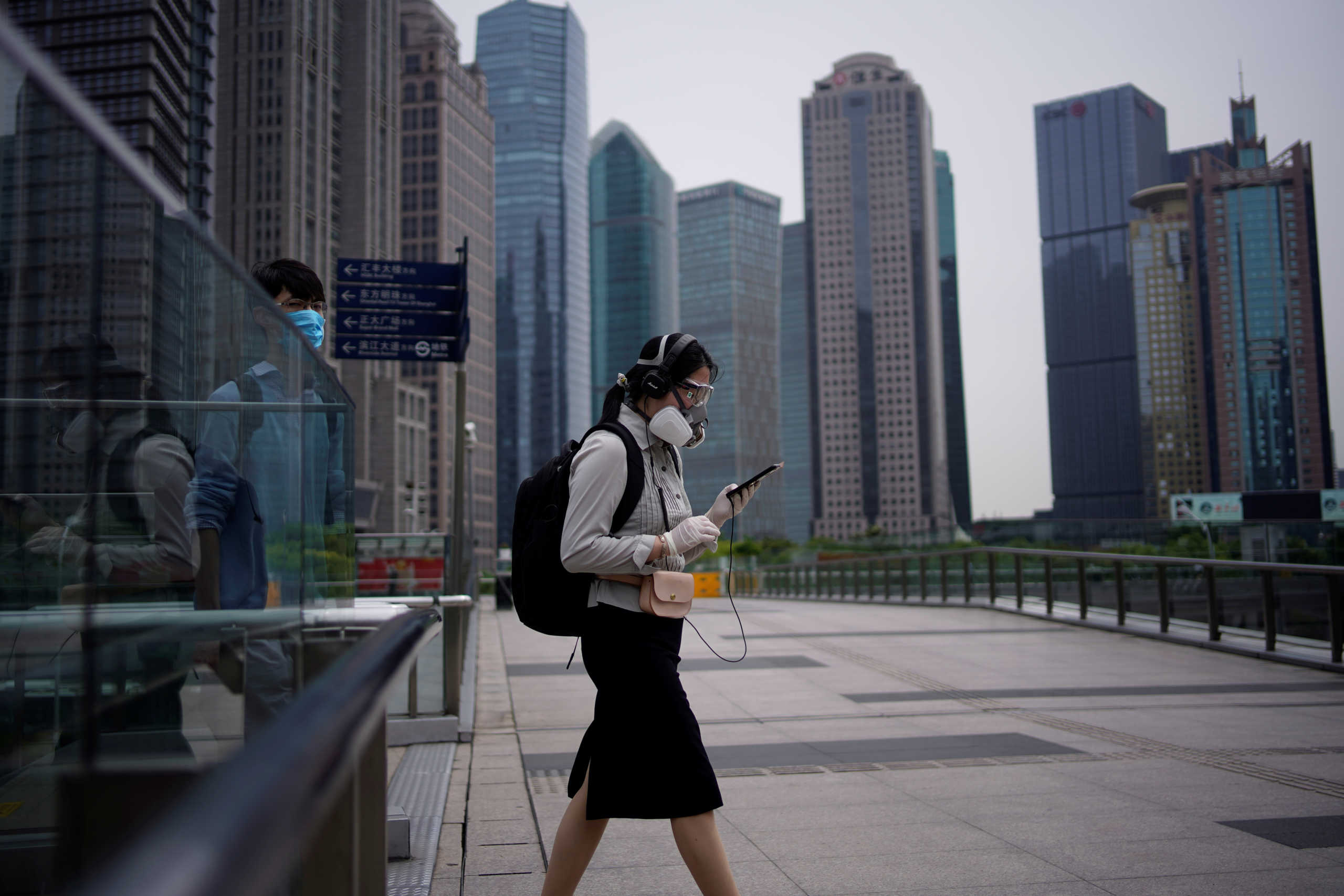 People wearing protective face masks walk past office buildings in Lujiazui financial district in Pudong, in Shanghai, following the coronavirus disease (COVID-19) outbreak, China June 4, 2020. REUTERS
