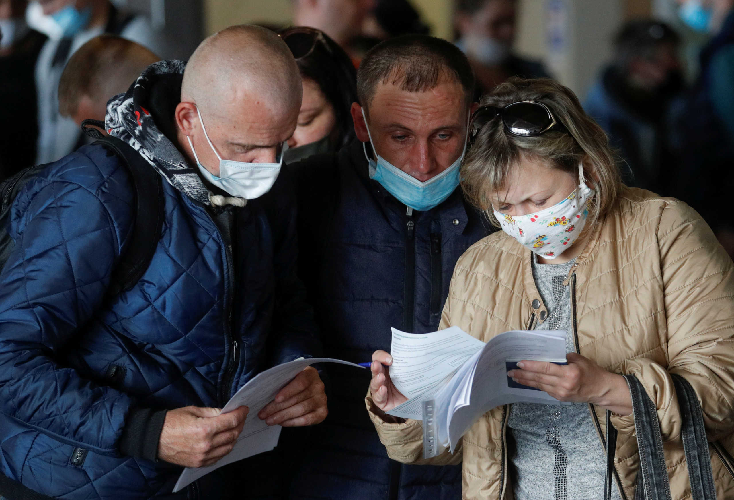 Ukrainian workers study check-in documents before their departure for Poland amid the outbreak of the coronavirus disease (COVID-19) at the Boryspil International Airport outside Kiev, Ukraine May 24, 2020. First Ukrainian seasonal workers return to Poland as lockdown measures in both countries against the novel coronavirus pandemic begin to ease. Picture taken May 24, 2020. REUTERS