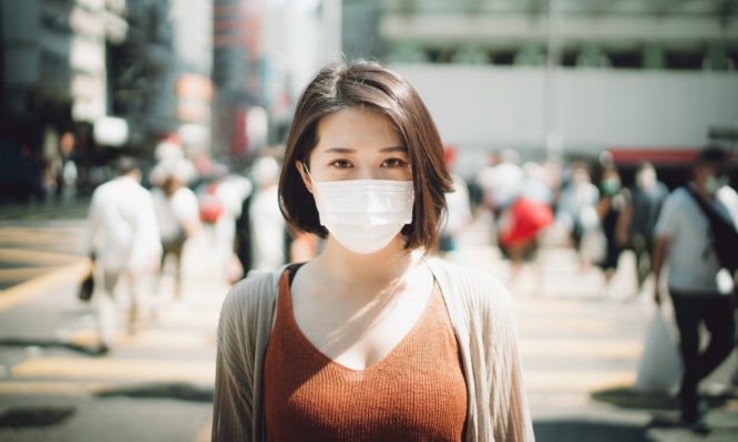 Young Asian woman wearing a protective face mask to prevent the spread of viruses in the city during the epidemic of Covid-19 health crisis