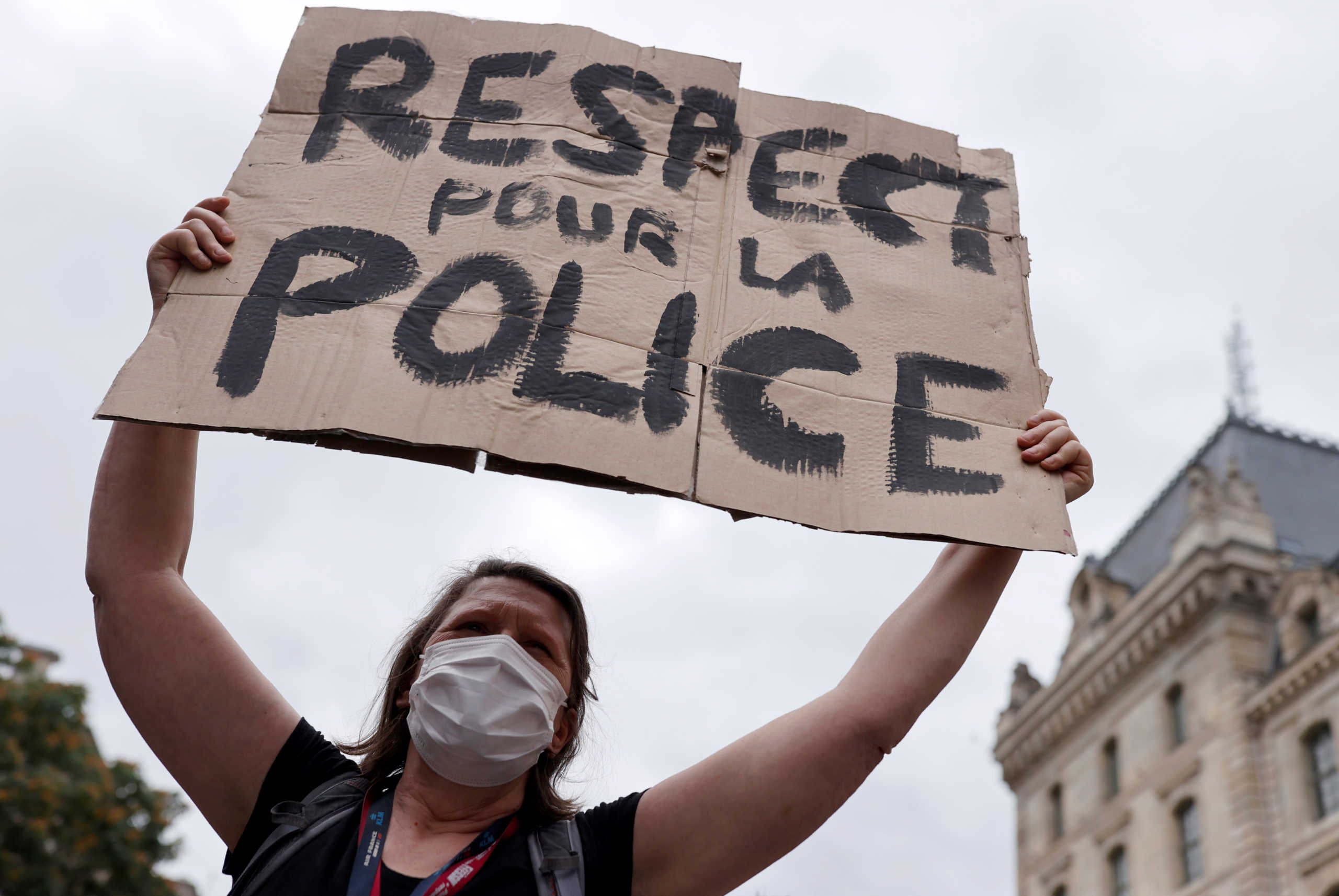 A supporter of police forces wearing a protective face mask holds a banner as she demonstrates in front of the French police headquarters in Paris, France June 27, 2020. The banner reads: "Respect for police" REUTERS