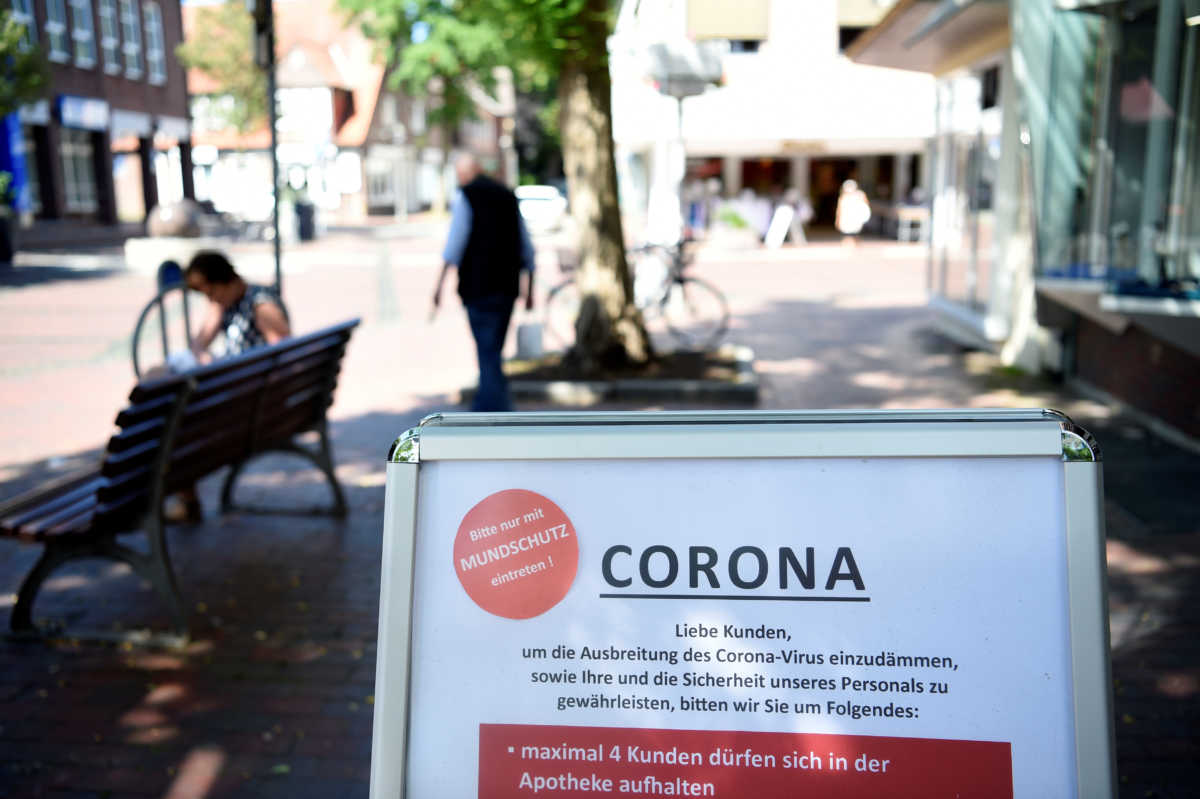 A banner reading "Entering only with a face mask please - only 4 clients are allowed in the pharmacy" is pictured in front of a pharmacy during the spread of the coronavirus disease (COVID-19) in downtown Wildeshausen, Germany June 24, 2020. REUTERS