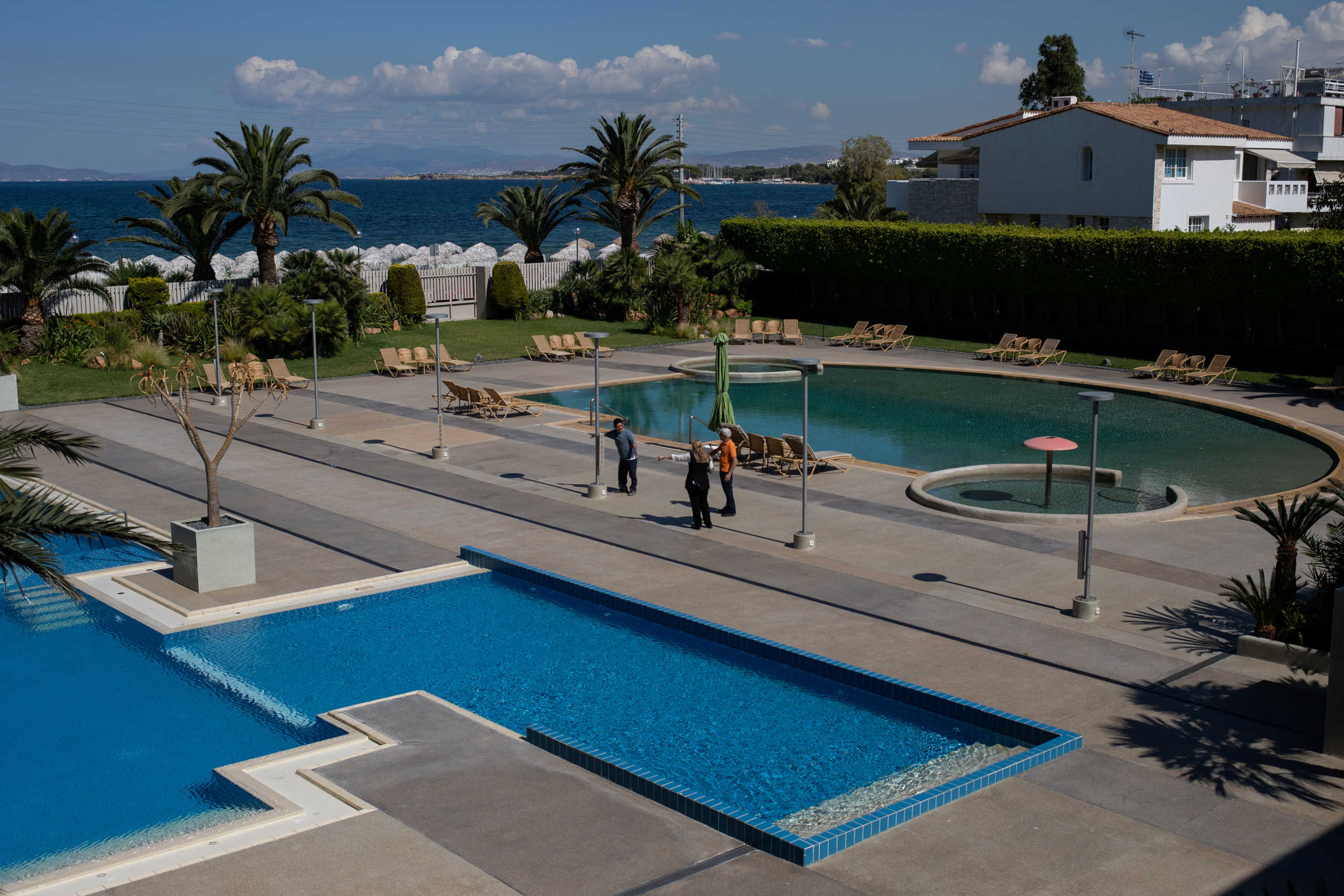 Employees discuss next to the swimming pools of the Divani Apollon Palace hotel, on the first day of the opening of hotels in Greece, following a nationwide lockdown against the spread of the coronavirus disease (COVID-19), in Athens, Greece, June 1, 2020. REUTERS