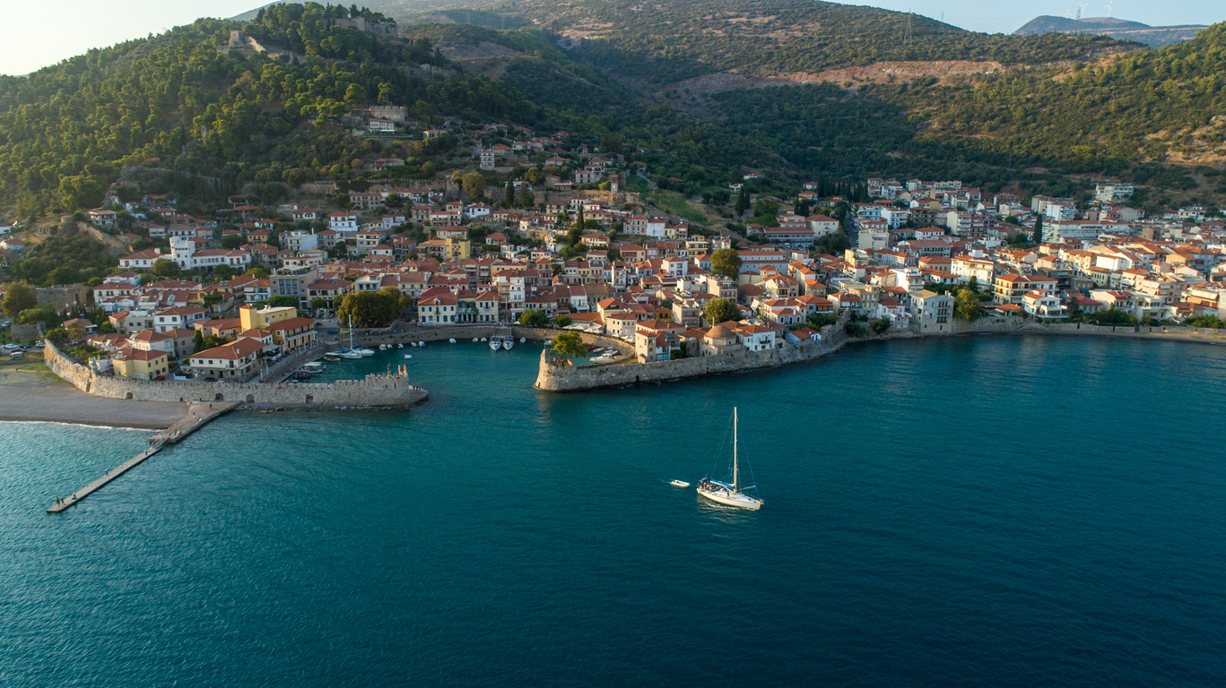 Aerial view of small town with nice marina Nafpaktos. This place is located on Greece mainland. Photo made with drone at sunset. One sailboat is near marina
