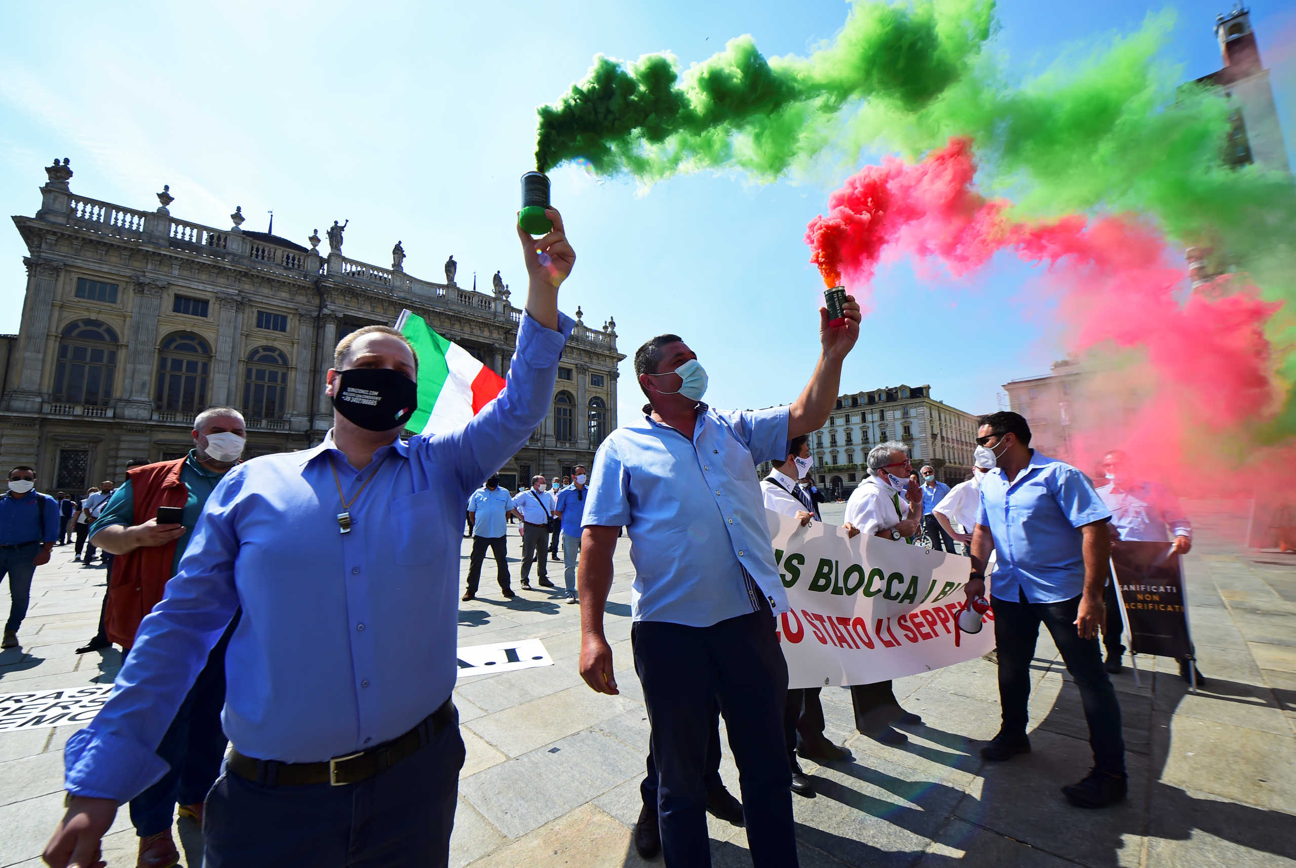 Protesters wearing protective face masks light flares as owners and drivers of tourist buses who have been without work for months due to Italy's lockdown hold a protest to demand financial help from the government, as the country relaxes more of its strict restrictions and allows free movement for the first time since the outbreak of the coronavirus disease (COVID-19), in Turin, Italy June 3, 2020. REUTERS