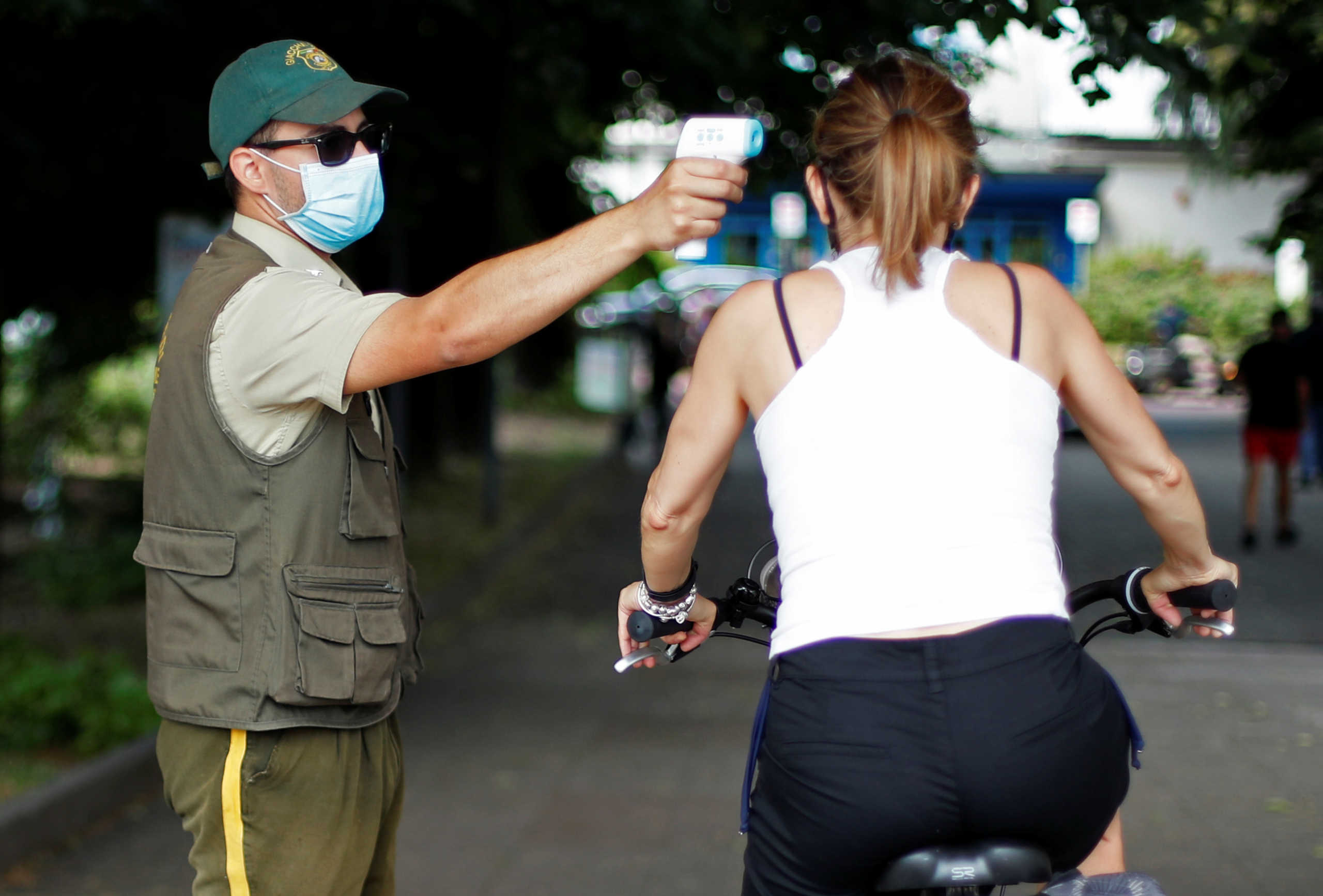 A cyclist has her temperature checked at the entrance of Idroscalo artificial lake, as Italy eases some of the lockdown measures put in place during the coronavirus disease (COVID-19) outbreak, in Milan, Italy, May 23, 2020. REUTERS