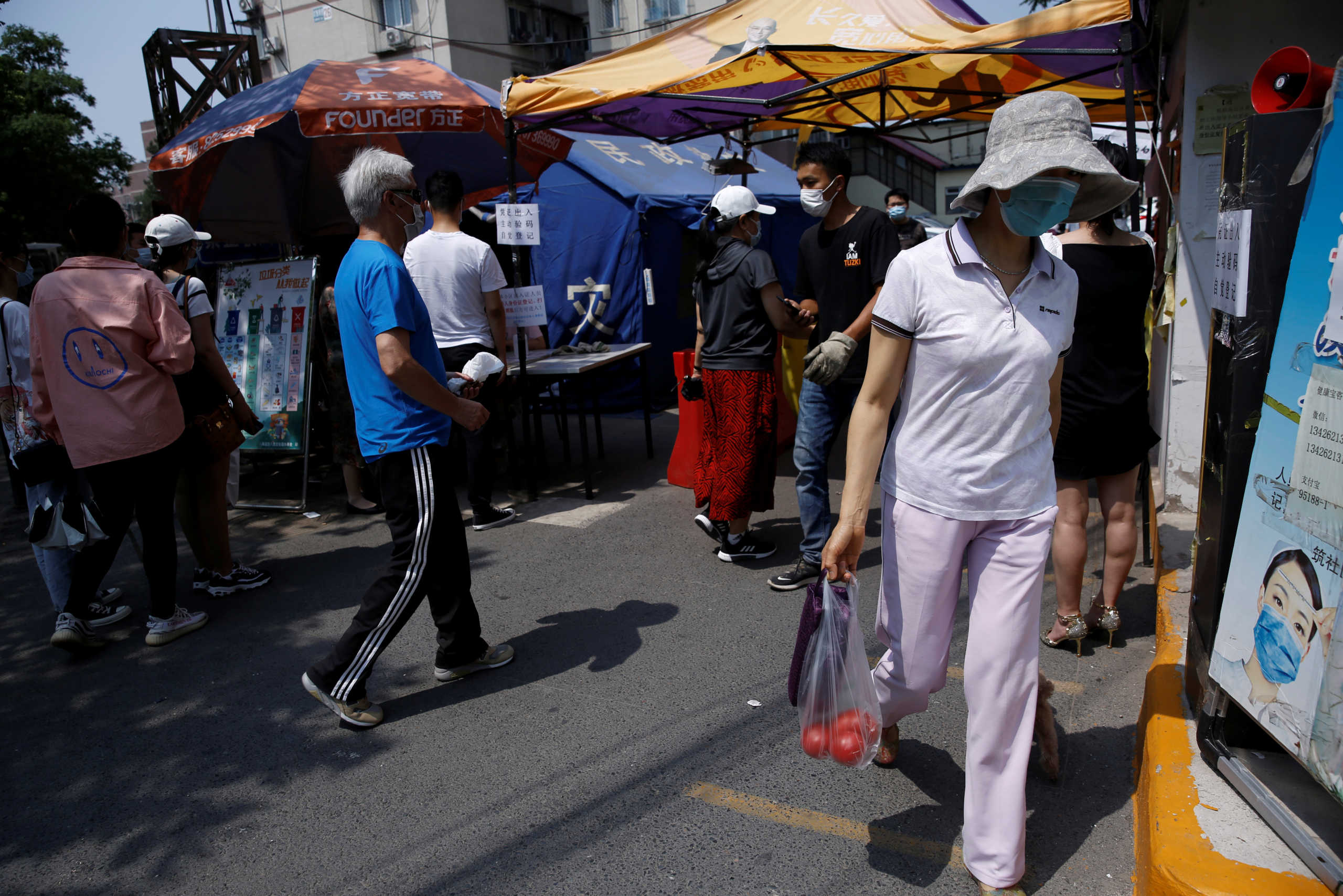 People wearing face mask are seen near tents for registration and temperature checks at an entrance to a residential compound, following a new outbreak of the coronavirus disease (COVID-19), in Beijing, China June 21, 2020. REUTERS