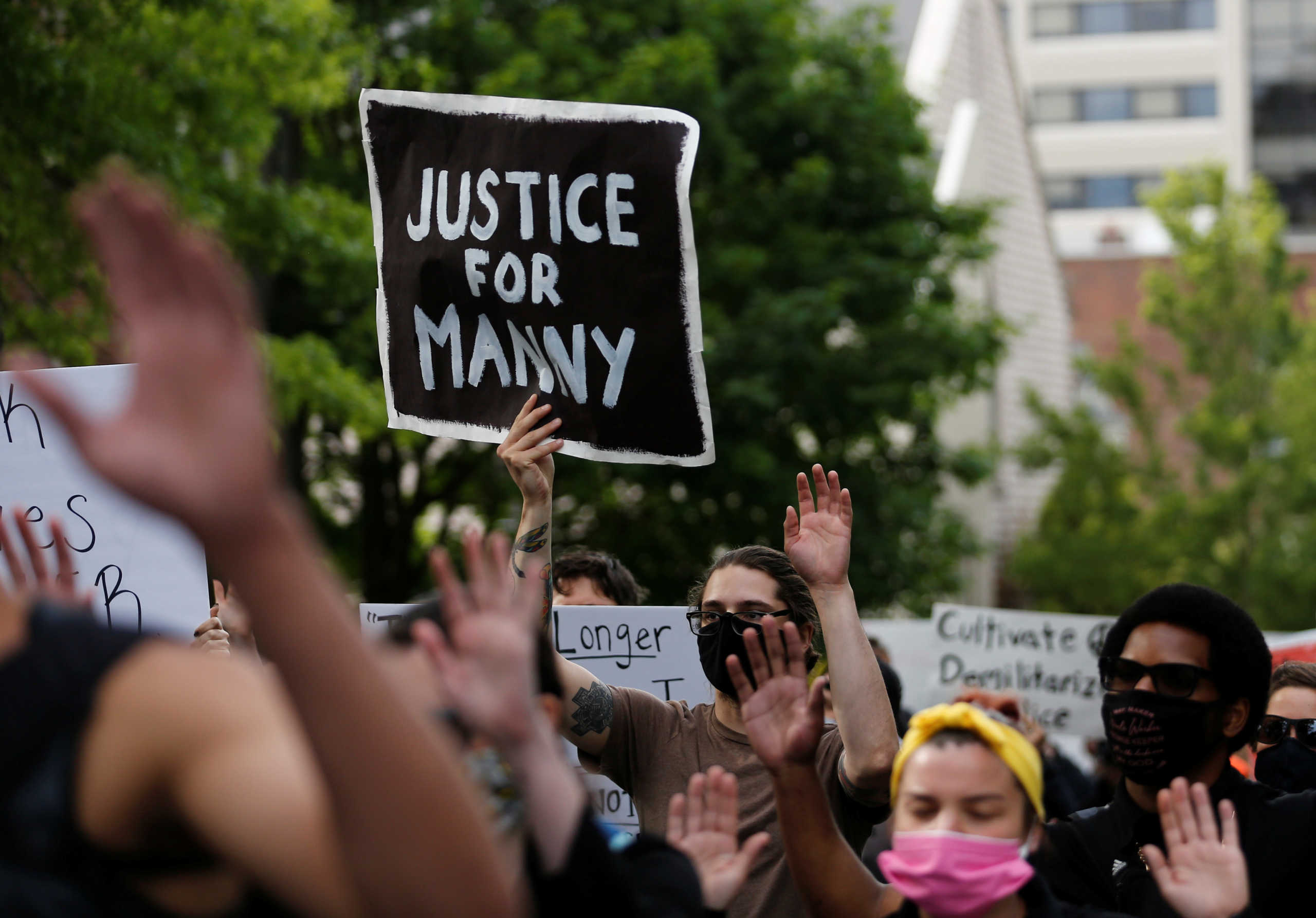 A protester holds a "Justice for Manny" sign as fellow protesters march following the death of Manuel Ellis in Tacoma police custody in March, and the death of George Floyd in Minneapolis police custody, in Tacoma, Washington, U.S. June 5, 2020. REUTERS