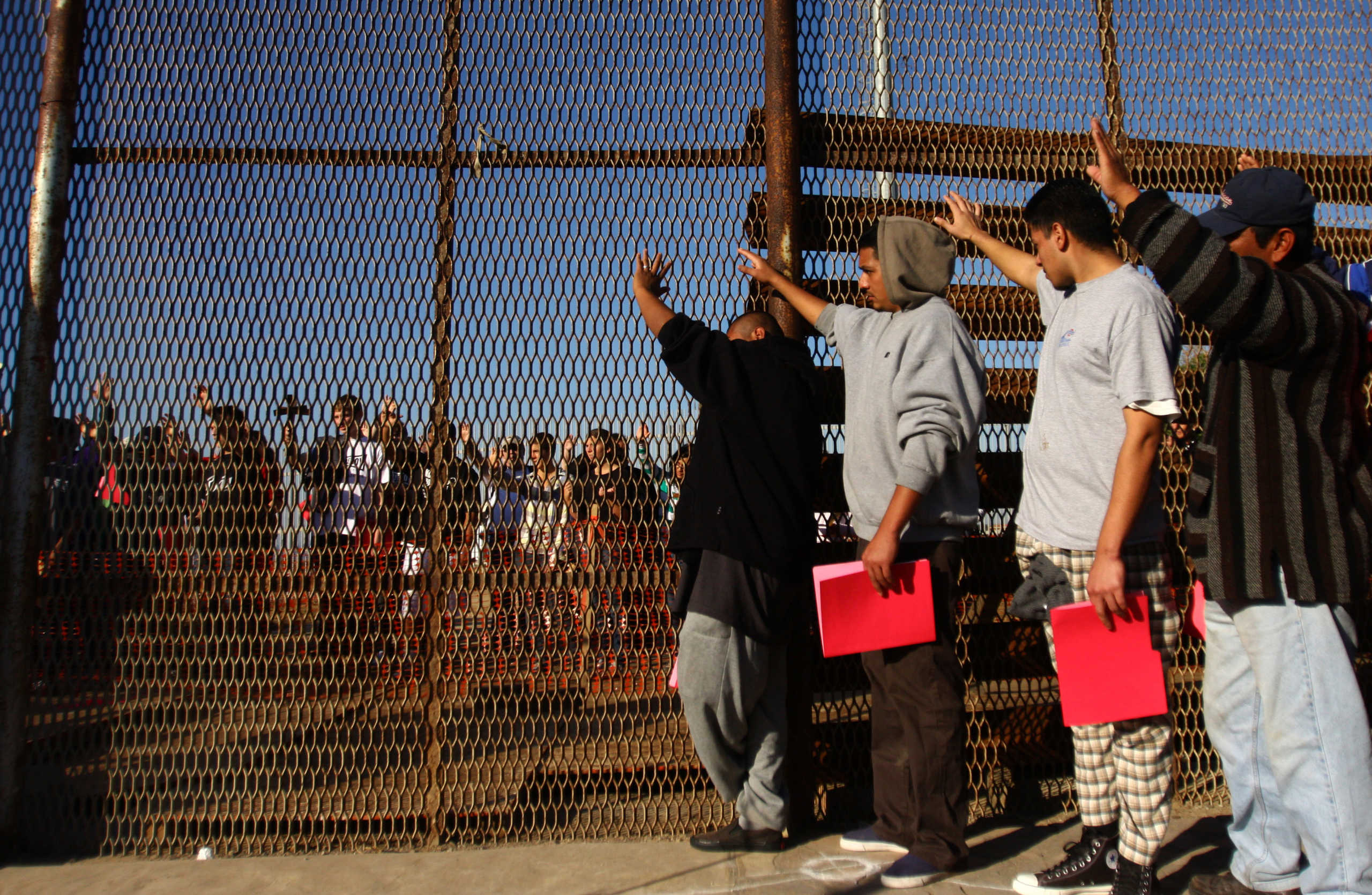 A group of recently deported immigrants stand near the double steel fence that separates San Diego and Tijuana at the border in Tijuana December 10, 2011. Immigrants rights organizations from the U.S and Mexico on Saturday organized an annual pre-Christmas celebration called "Posadas sin Fronteras" or "Christmas without borders", which more than 200 people from both sides attended on the Tijuana and San Diego border. REUTERS