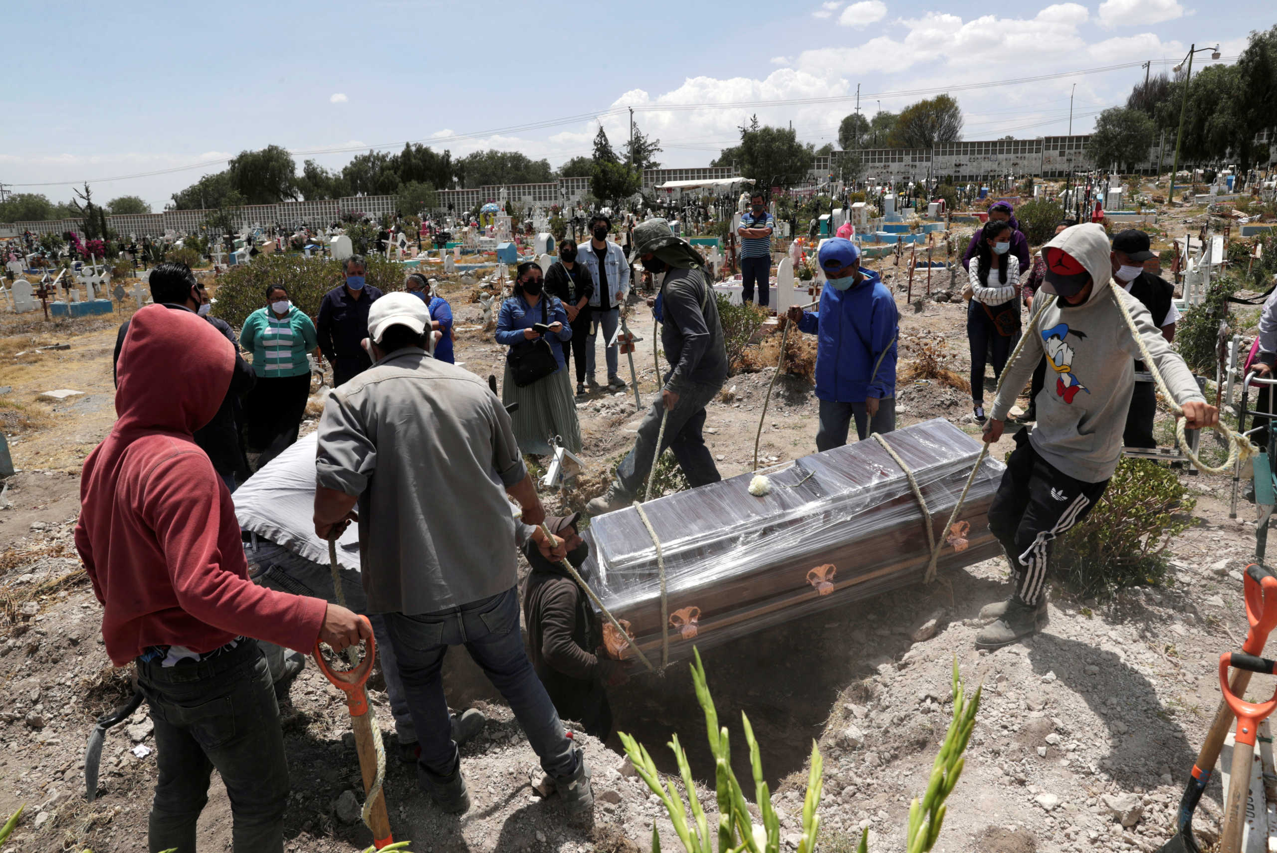 Cemetery workers move the coffin of a woman, who died of the coronavirus disease (COVID-19), during her funeral at the San Isidro Municipal cemetery, as the coronavirus disease (COVID-19) outbreak continues, in Ecatepec de Morelos, on the outskirts of Mexico City, Mexico June 19, 2020. REUTERS