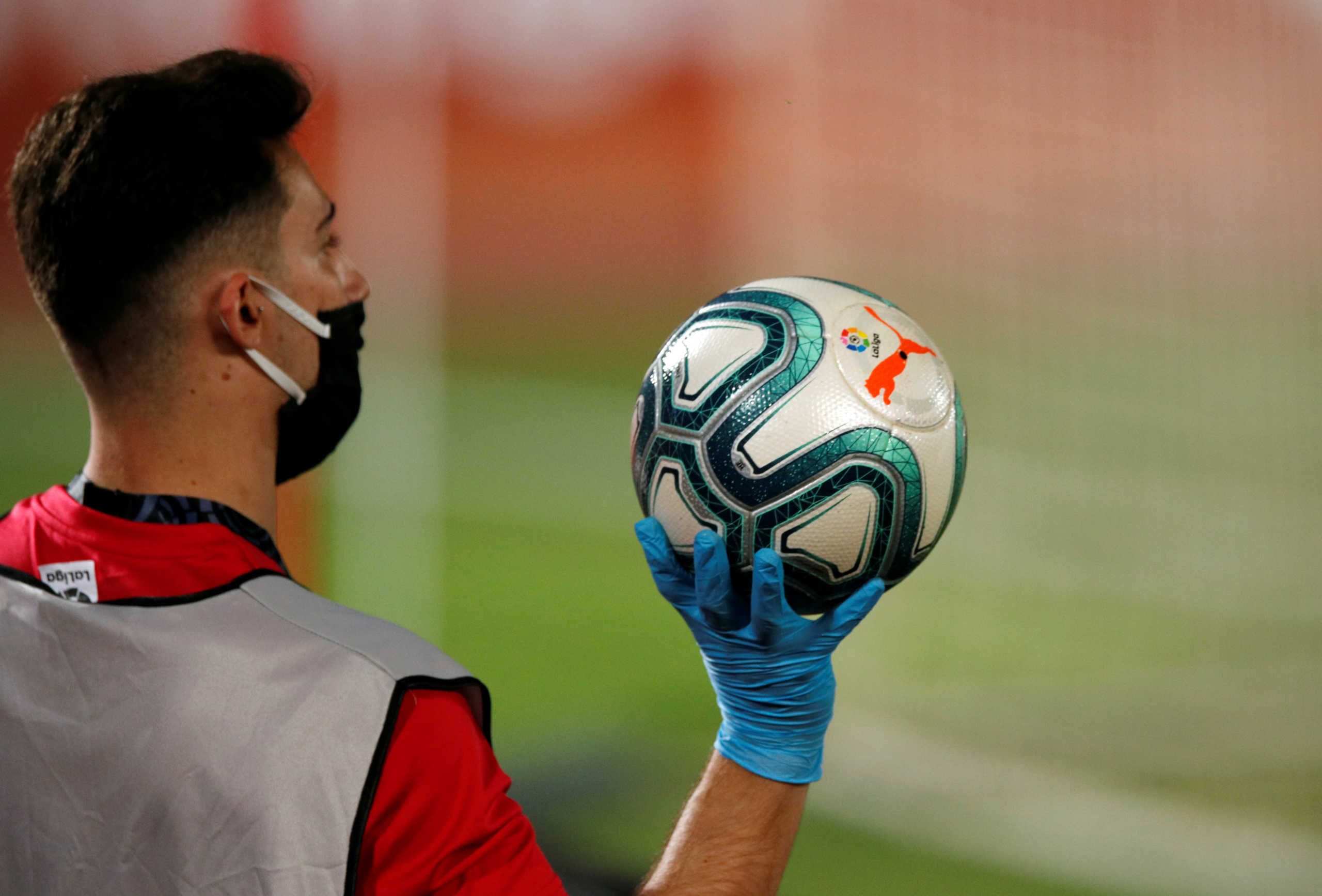 Soccer Football - La Liga Santander - RCD Mallorca v FC Barcelona - Iberostar Stadium, Palma, Spain - June 13, 2020   A ballboy wearing a protective face mask and gloves with the matchball, as play resumes behind closed doors following the outbreak of the coronavirus disease (COVID-19)   REUTERS