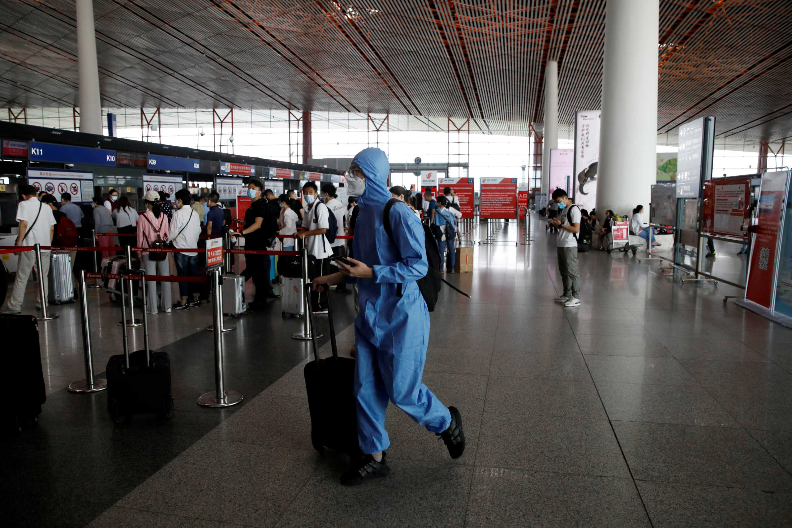 A traveler wearing protective gear walks with luggage at the departure hall of Beijing Capital International Airport after scores of domestic flights in and out of the Chinese capital were cancelled following the new outbreak of the coronavirus disease (COVID-19) in Beijing, China June 17, 2020. REUTERS