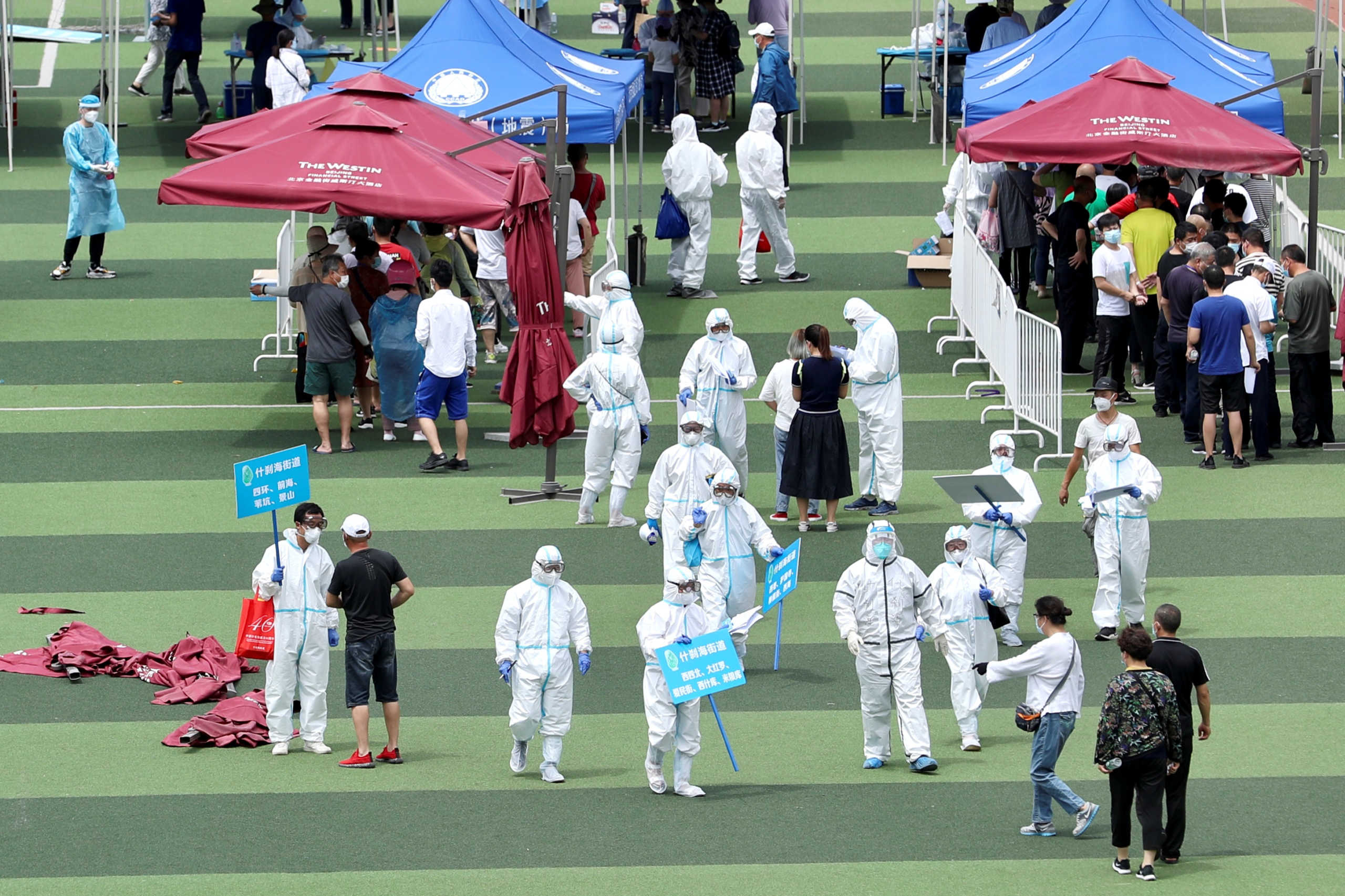 Medical workers in protective suits help people lining up inside a sports centre for nucleic acid tests, following new cases of coronavirus disease (COVID-19) infections in Beijing, China June 15, 2020. China Daily via REUTERS  ATTENTION EDITORS - THIS IMAGE WAS PROVIDED BY A THIRD PARTY. CHINA OUT.