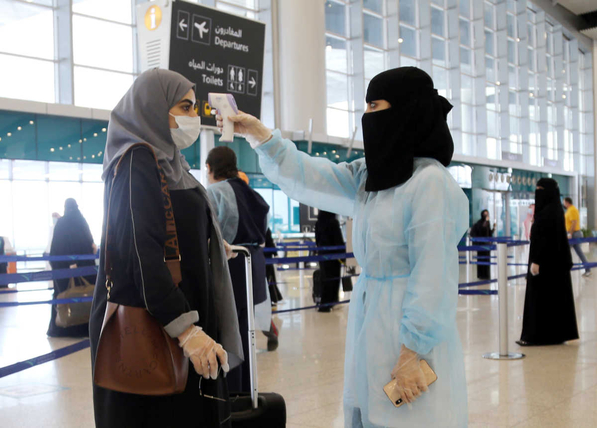 A security woman checks the temperature of a woman at Riyadh International Airport, after Saudi Arabia reopened domestic flights, following the outbreak of the coronavirus disease (COVID-19), in Riyadh, Saudi Arabia May 31, 2020. REUTERS