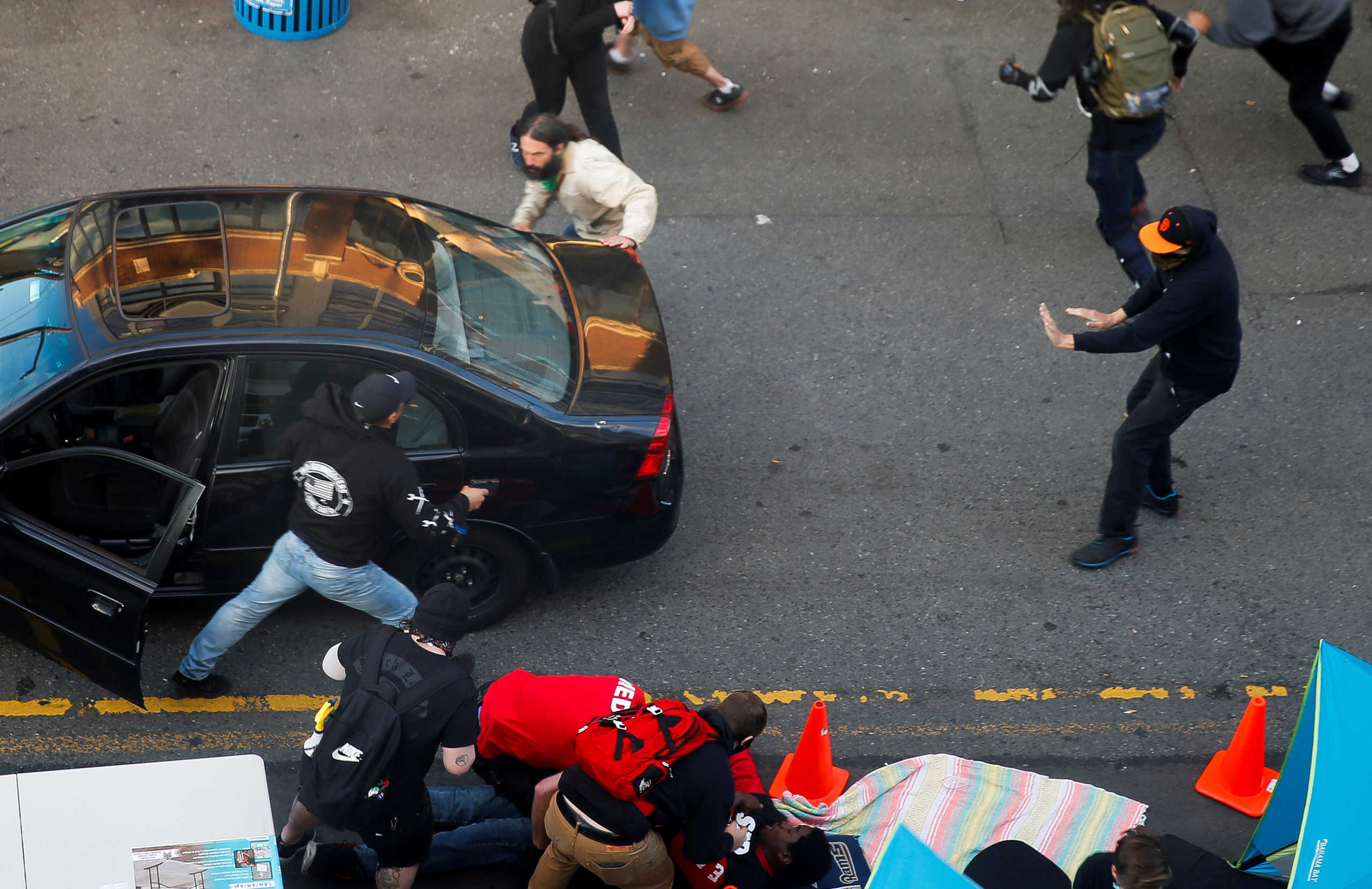 A man exits a vehicle with a gun as a man is tended to by medics after being shot by a driver who tried to drive through a protest against racial inequality in the aftermath of the death in Minneapolis police custody of George Floyd, in Seattle, Washington, U.S. June 7, 2020. REUTERS