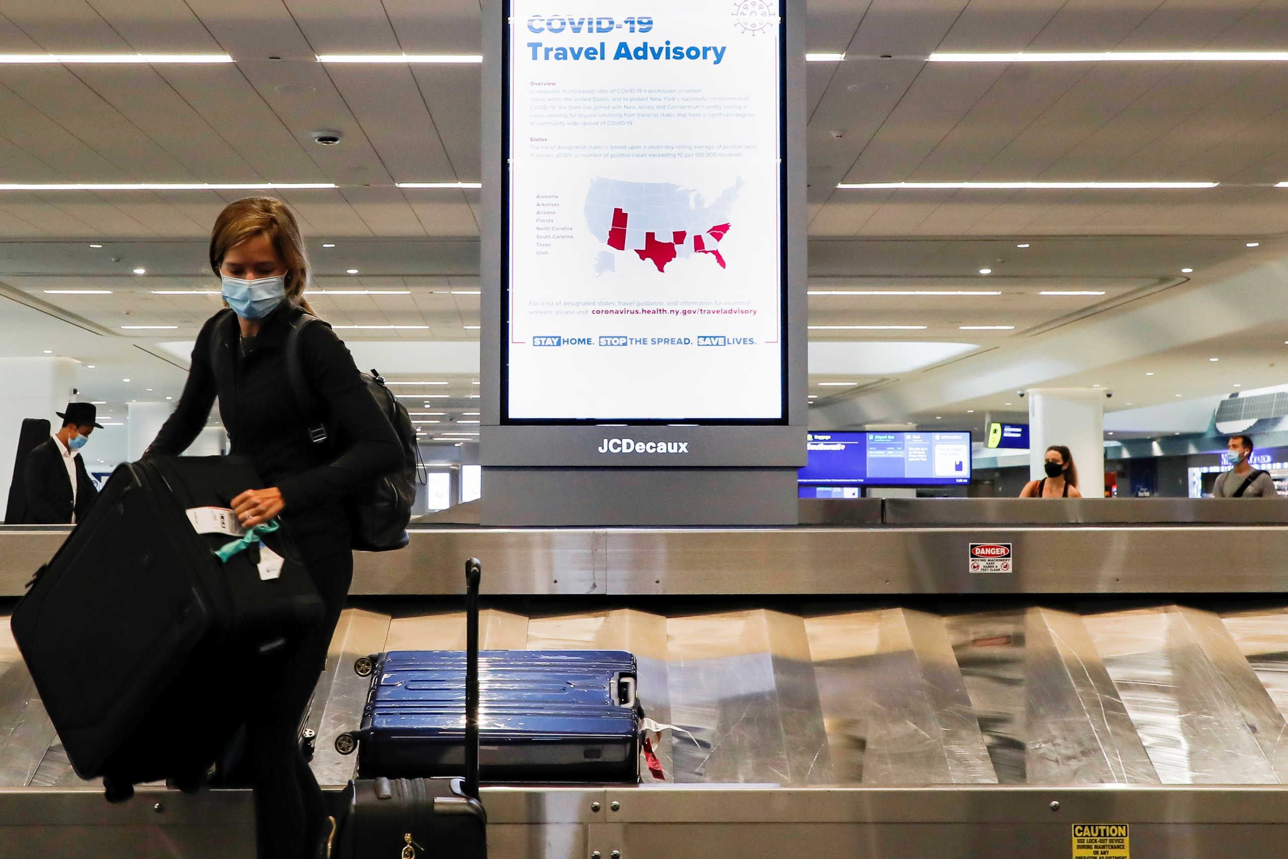 A sign alerts travelers to the danger of COVID-19 at LaGuardia Airport, during the outbreak of the coronavirus disease (COVID-19), in New York, U.S., June 29, 2020. REUTERS