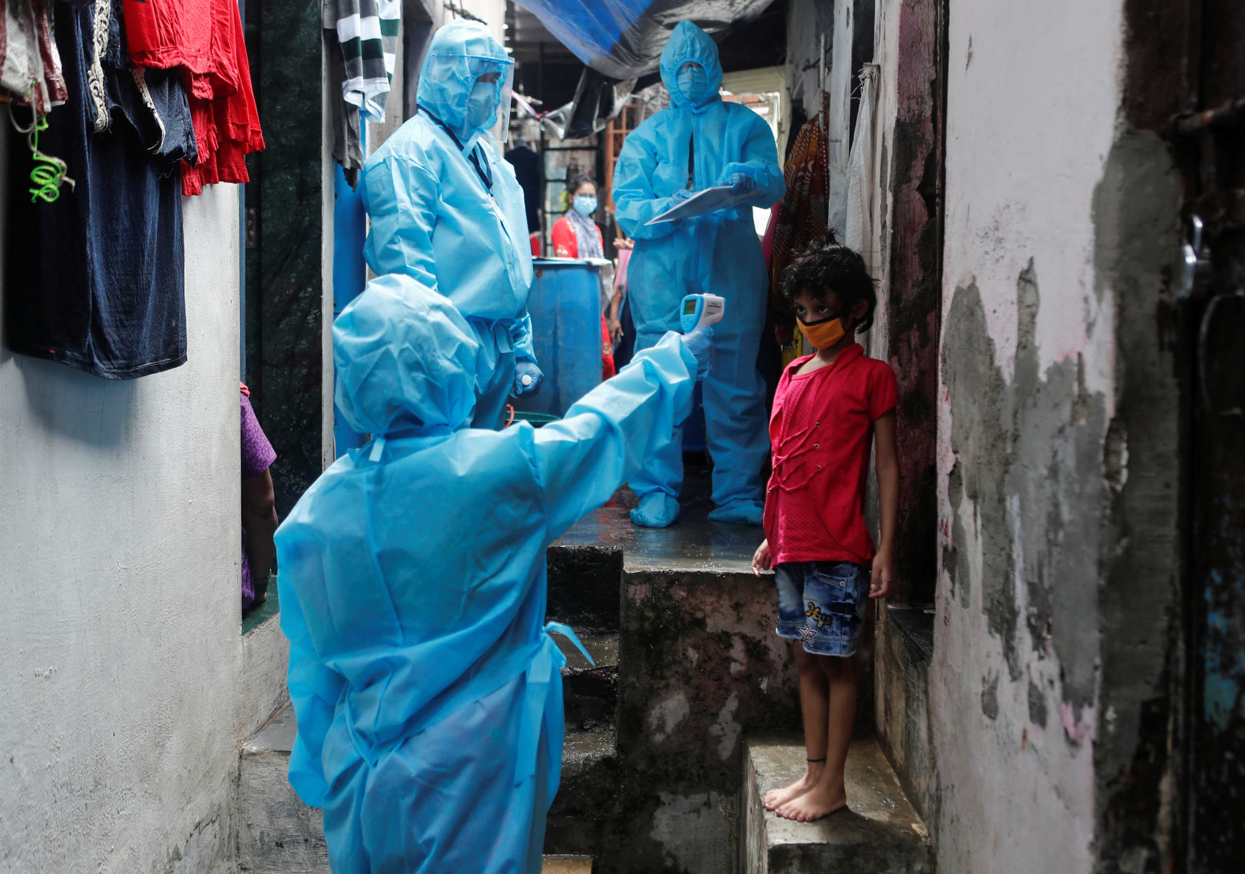 A healthcare worker checks the temperature of a resident during a medical campaign for the coronavirus disease (COVID-19) at a slum area in Mumbai, India, July 1, 2020. REUTERS