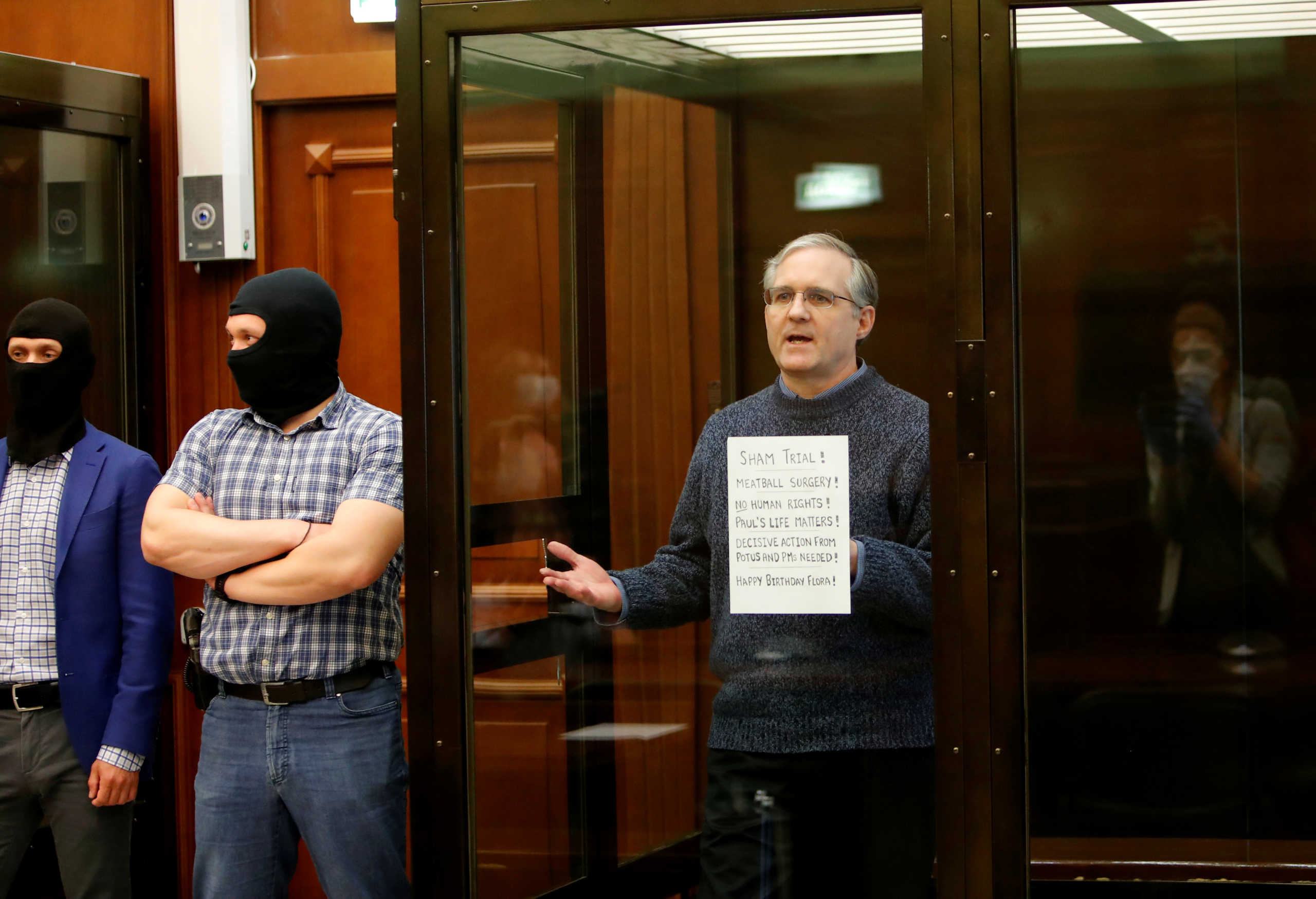 FILE PHOTO: Former U.S. Marine Paul Whelan, who was detained and accused of espionage, holds a sign as he stands inside a defendants' cage during his verdict hearing in Moscow, Russia June 15, 2020. REUTERS