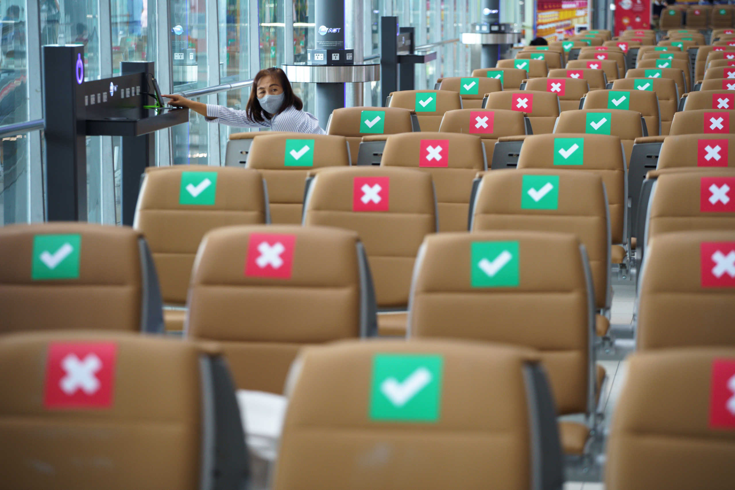 A tourist wearing a protective mask sits on a social distancing seat as she waits for her flight at Bangkok's Suvarnabhumi International airport amid the spread of the coronavirus disease (COVID-19), Thailand, June 3, 2020. REUTERS