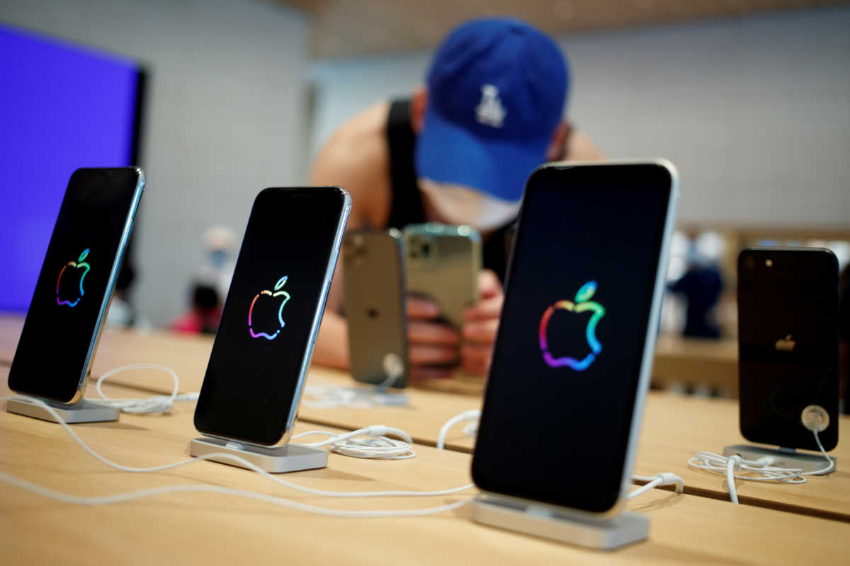 FILE PHOTO: A man takes pictures of iPhones in the new Apple flagship store on its opening day following an outbreak of the coronavirus disease (COVID-19) in Sanlitun in Beijing, China, July 17, 2020. REUTERS