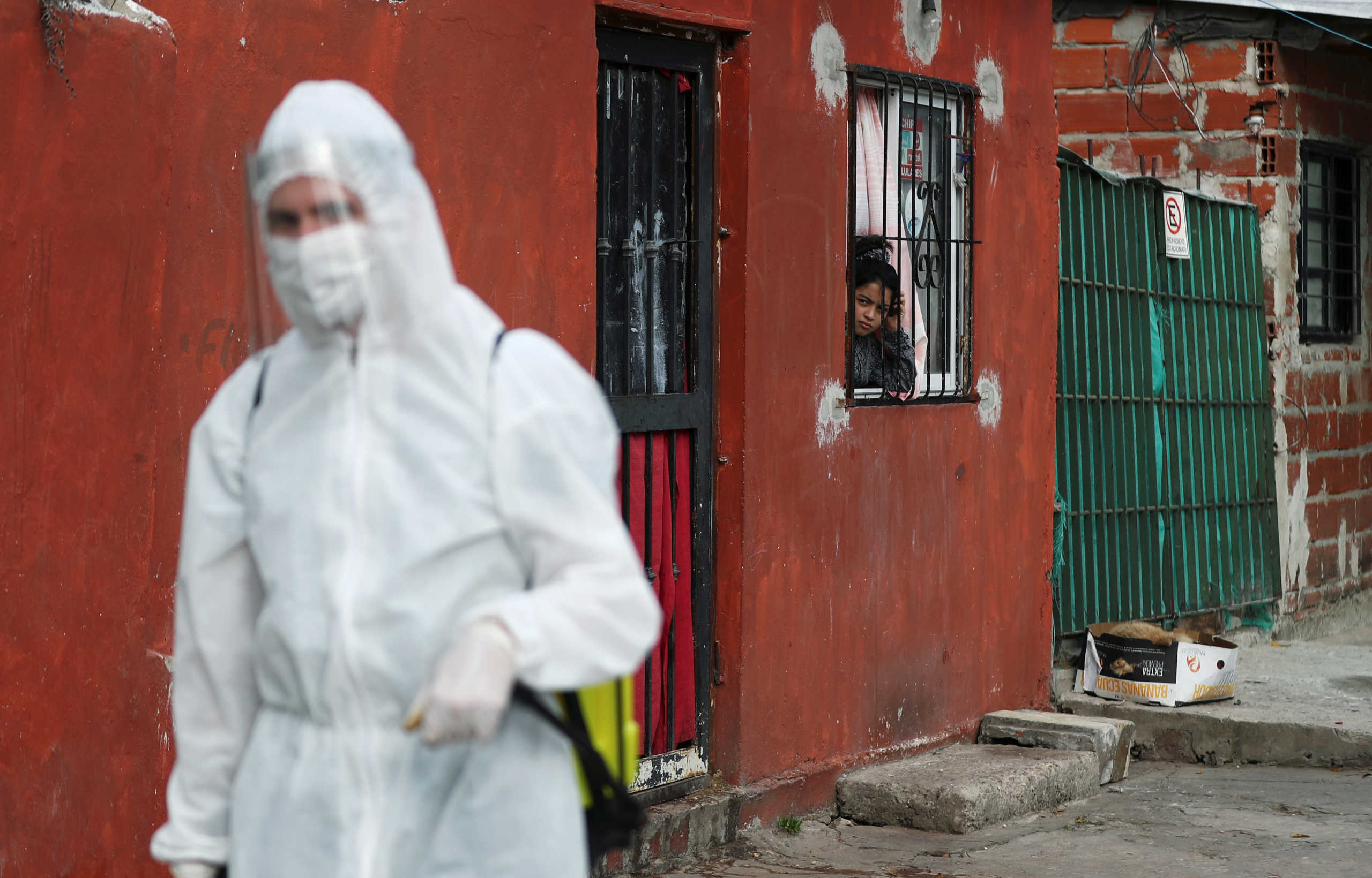 A child looks at a worker as he disinfects an area as a preventive measure against the coronavirus disease (COVID-19), in Beccar, on the outskirts of Buenos Aires, Argentina June 17, 2020. REUTERS