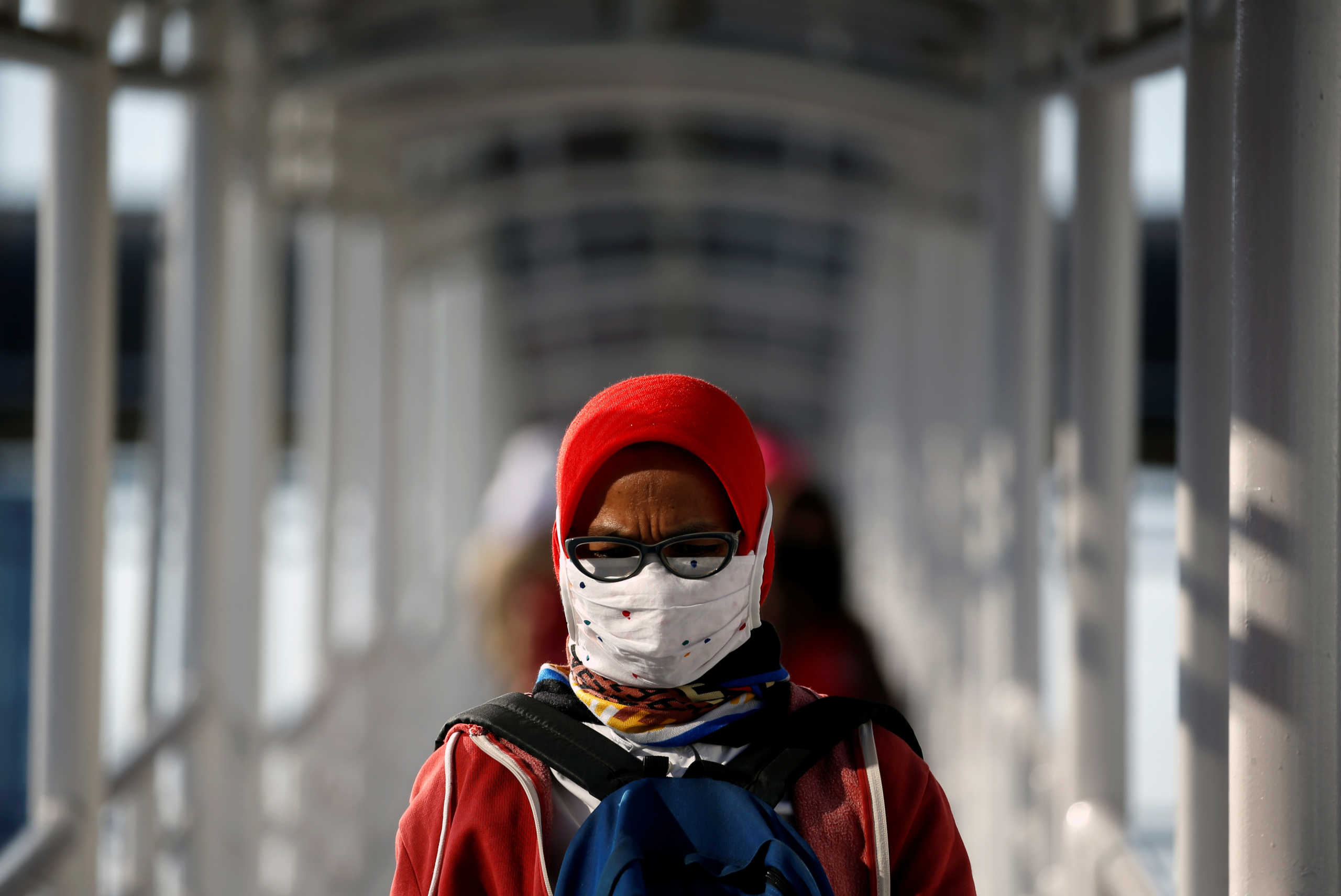 A woman wearing a protective mask and a face shield walks on a pedestrian bridge, following the coronavirus disease (COVID-19) outbreak, in Jakarta, Indonesia, July 27, 2020. REUTERS