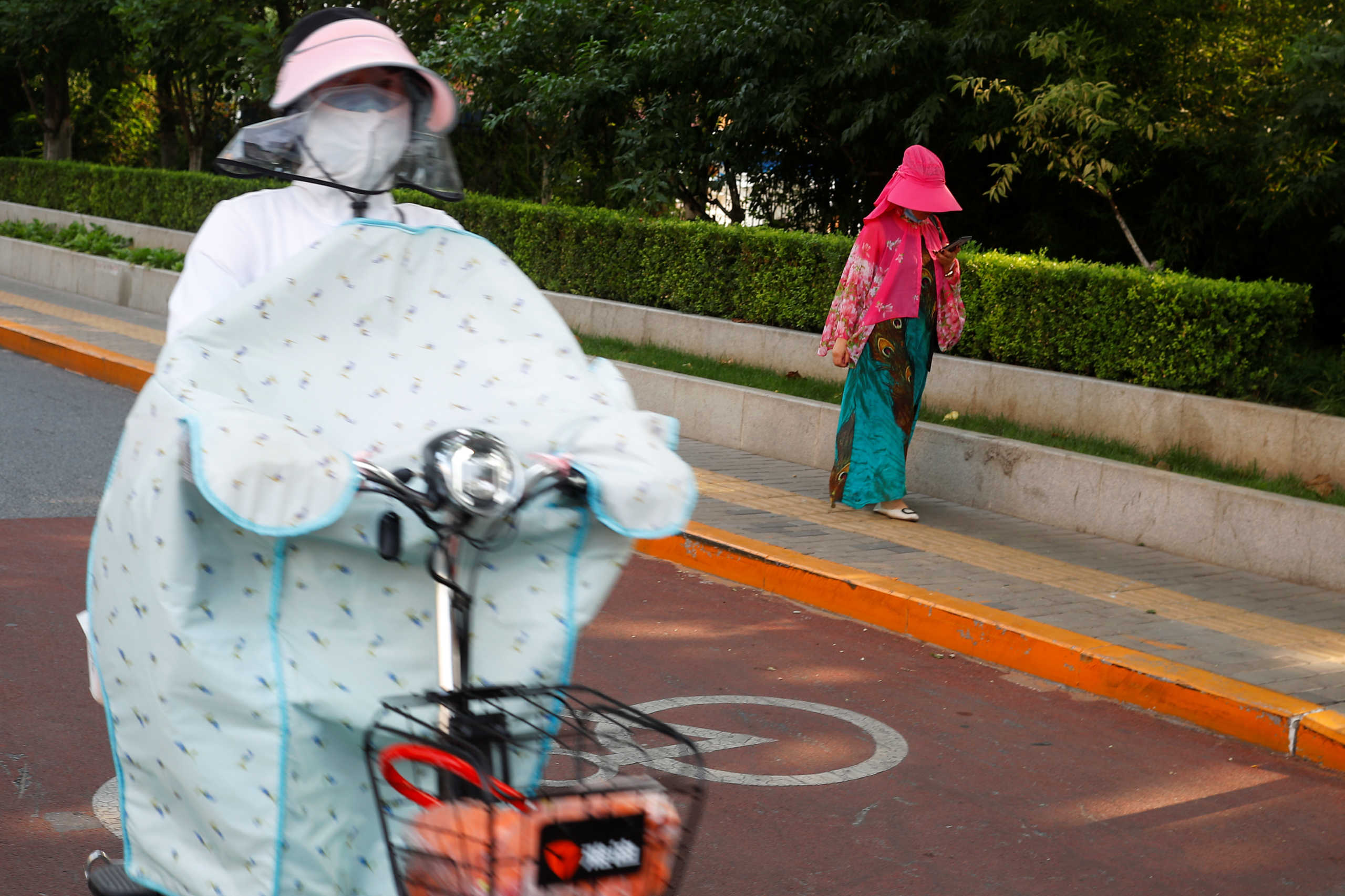 Women wear clothes that protect them from the sun on a hot day, following the coronavirus disease (COVID-19) outbreak, in Beijing, China July 16, 2020. REUTERS