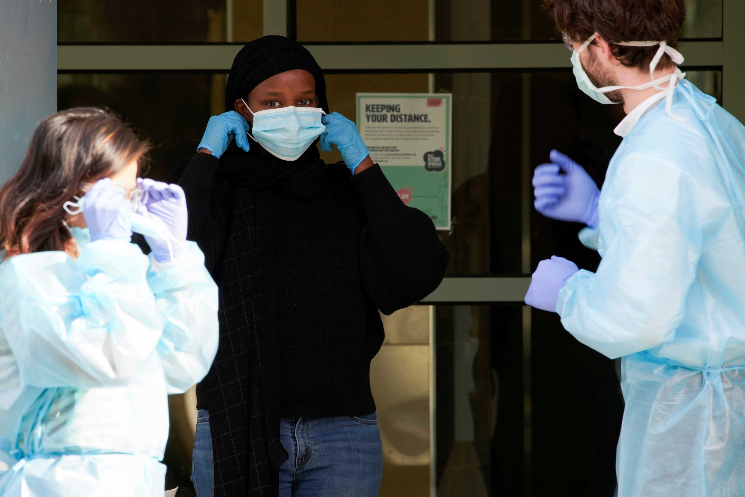 Healthcare workers assist a resident in putting her mask on outside of a public housing tower, reopened the previous night after being locked down in response to an outbreak of the coronavirus disease (COVID-19), in Melbourne, Australia, July 10, 2020. REUTERS