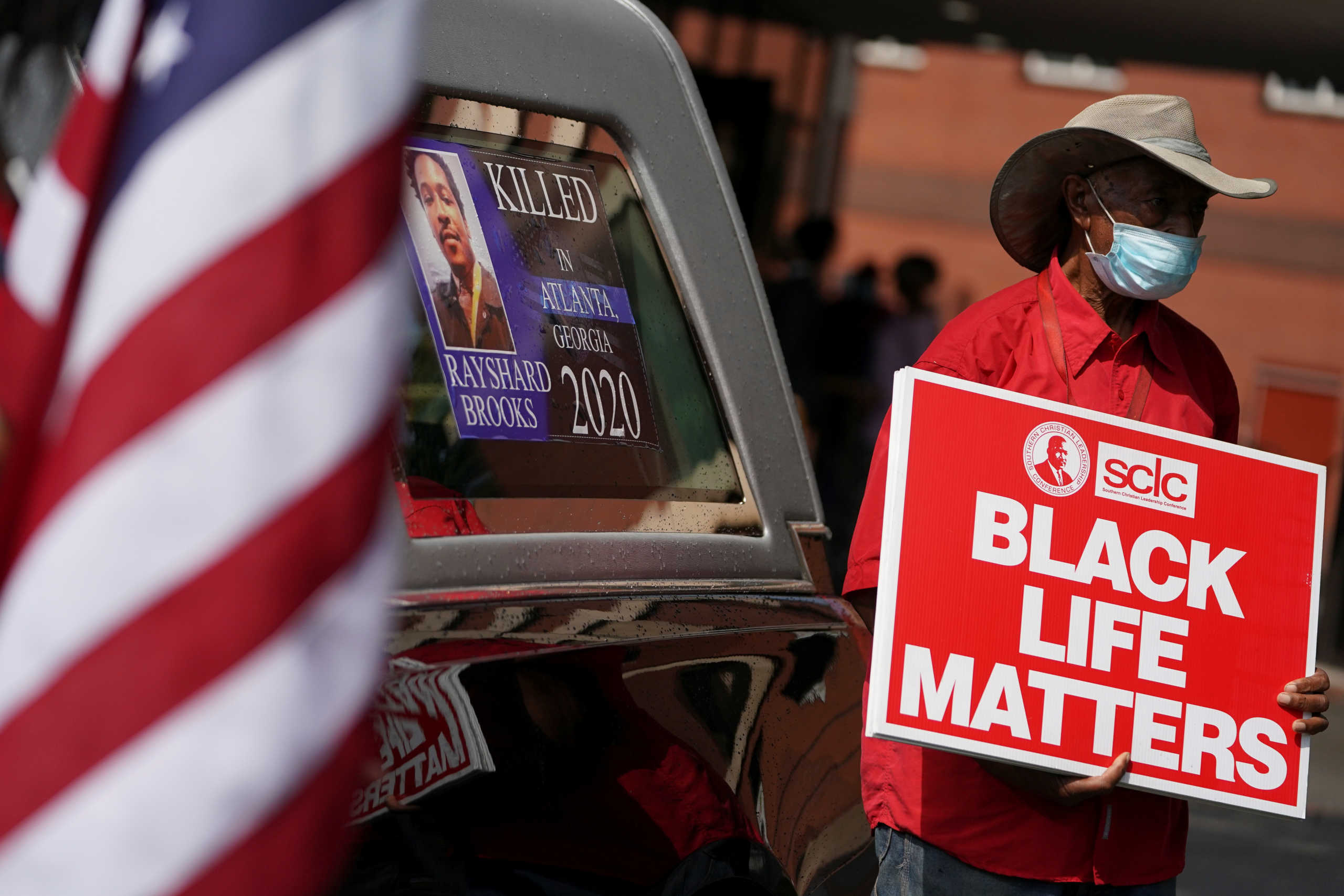 A man holds a sign next to a hearse at the public viewing for Rayshard Brooks, the Black man shot dead by an Atlanta police officer, at Ebenezer Baptist Church in Atlanta, Georgia, U.S. June 22, 2020.  REUTERS