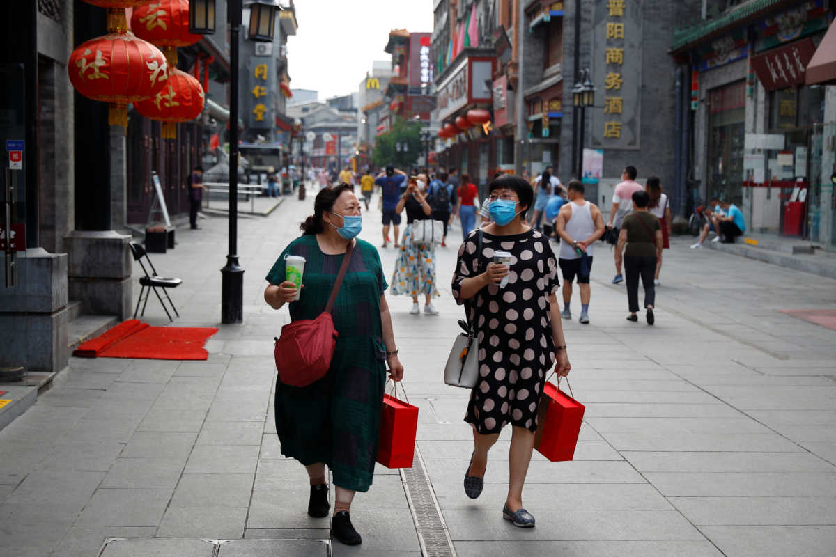 People wear protective masks as they walk in a shopping street following the outbreak of the coronavirus disease (COVID 19) in a historic part of Beijing, China, July 30, 2020. REUTERS