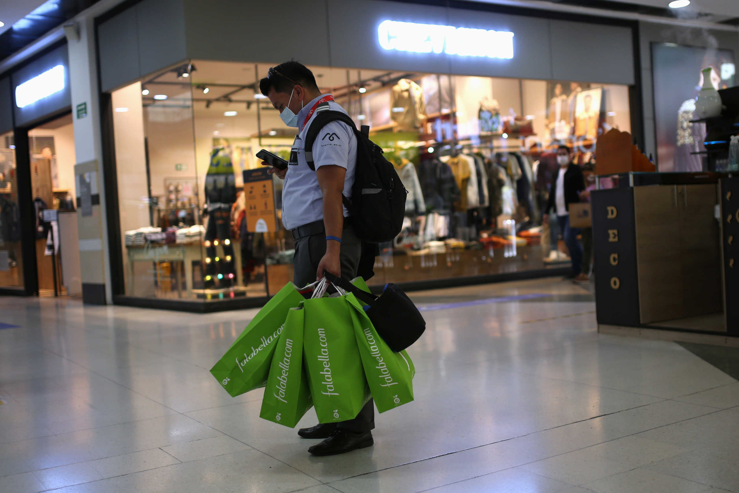 A man wearing a face mask carries some shopping bags inside a mall during an one-day lifting of sales tax, amid the outbreak of the coronavirus disease (COVID-19), in Bogota, Colombia July 3, 2020. REUTERS