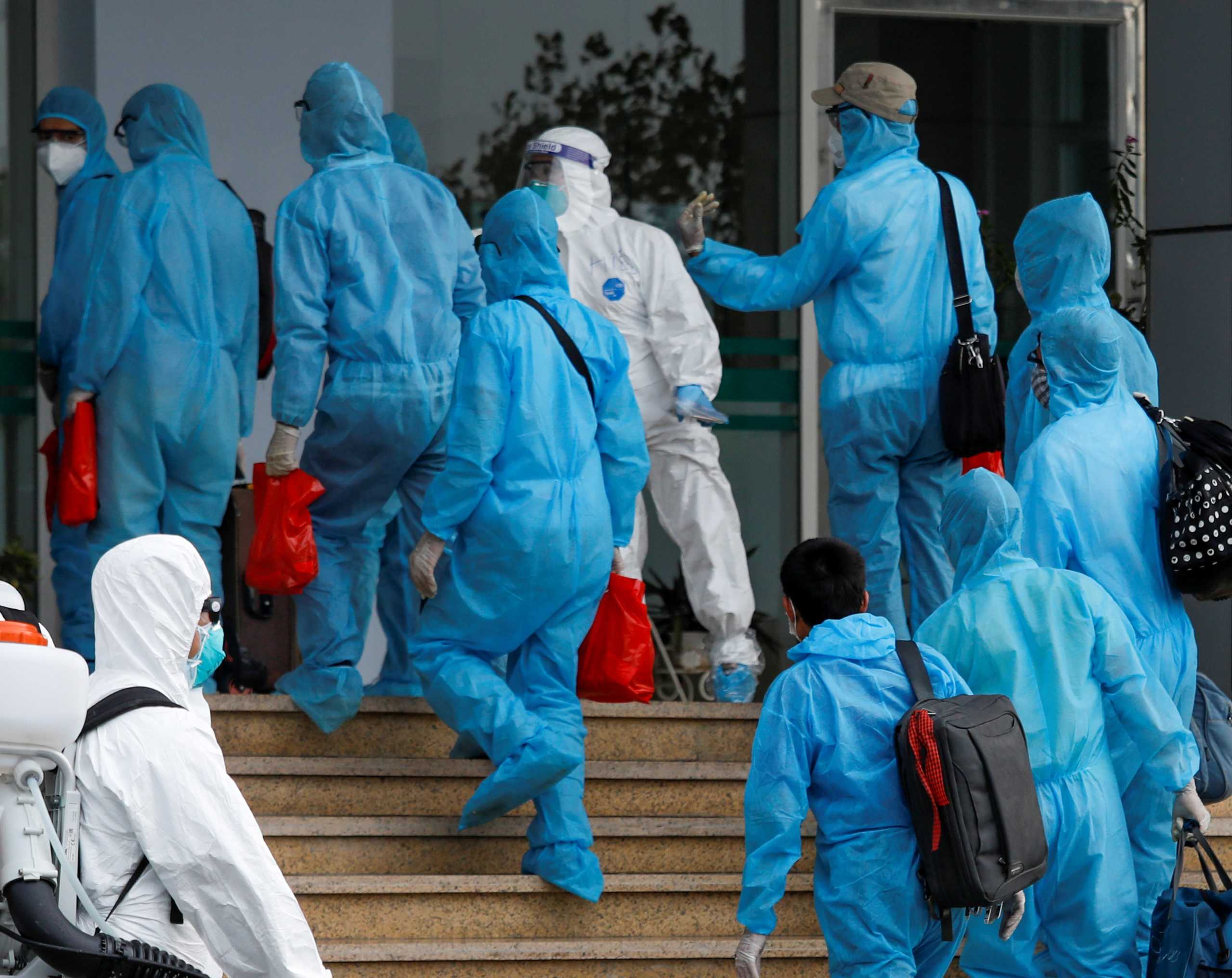 Vietnamese construction workers in blue protective suits infected with the coronavirus disease (COVID-19) arrive at the tropical diseases hospital after being repatriated from Equatorial Guinea via a specially-adapted Vietnam Airlines plane filled with medical equipment and negative pressure chambers, in Hanoi, Vietnam July 29, 2020. REUTERS