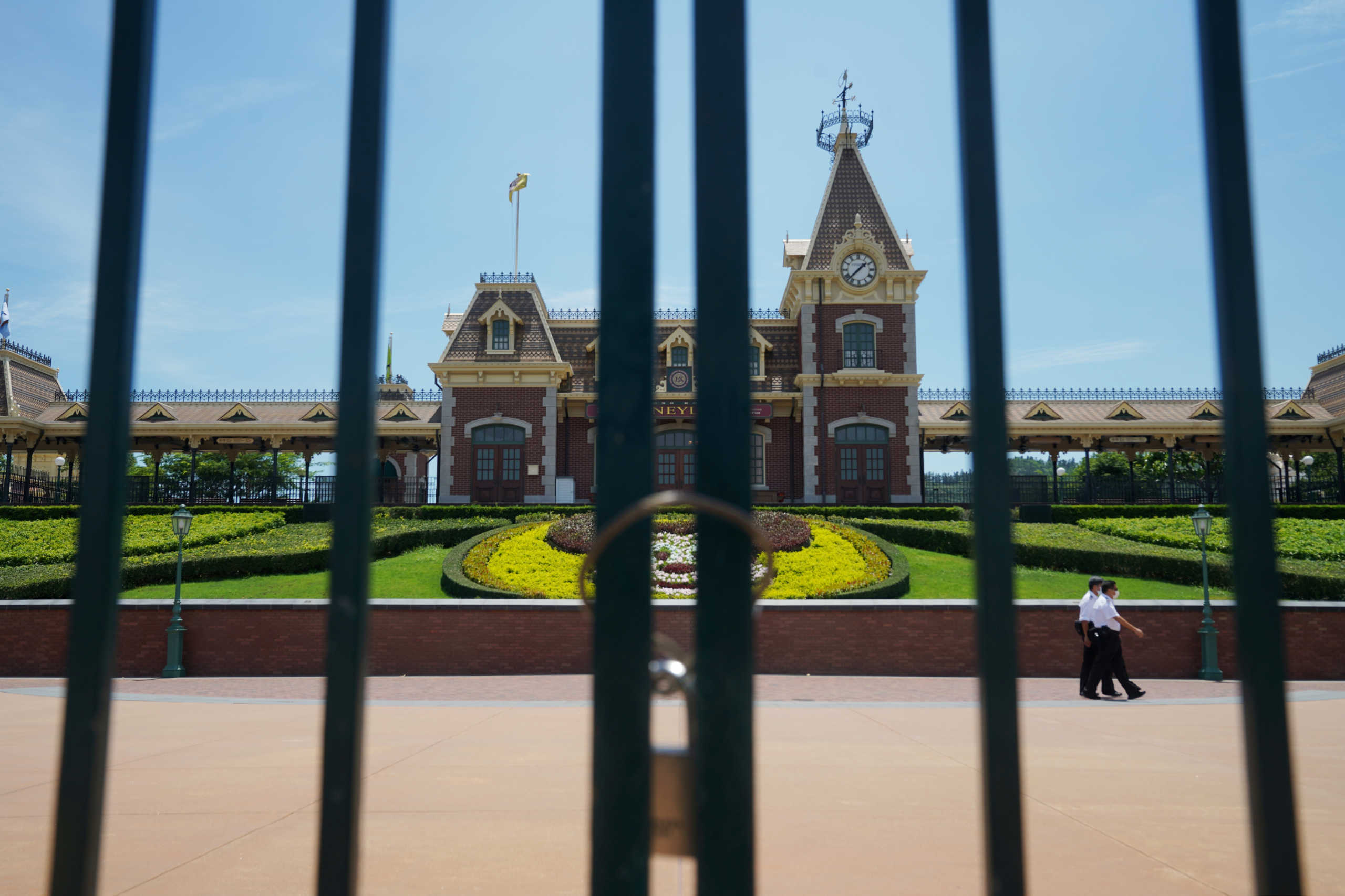 Men wearing face masks following the coronavirus disease (COVID-19) outbreak walk behind a closed gate at the Hong Kong Disneyland Resort in Hong Kong, China July 14, 2020.  REUTERS