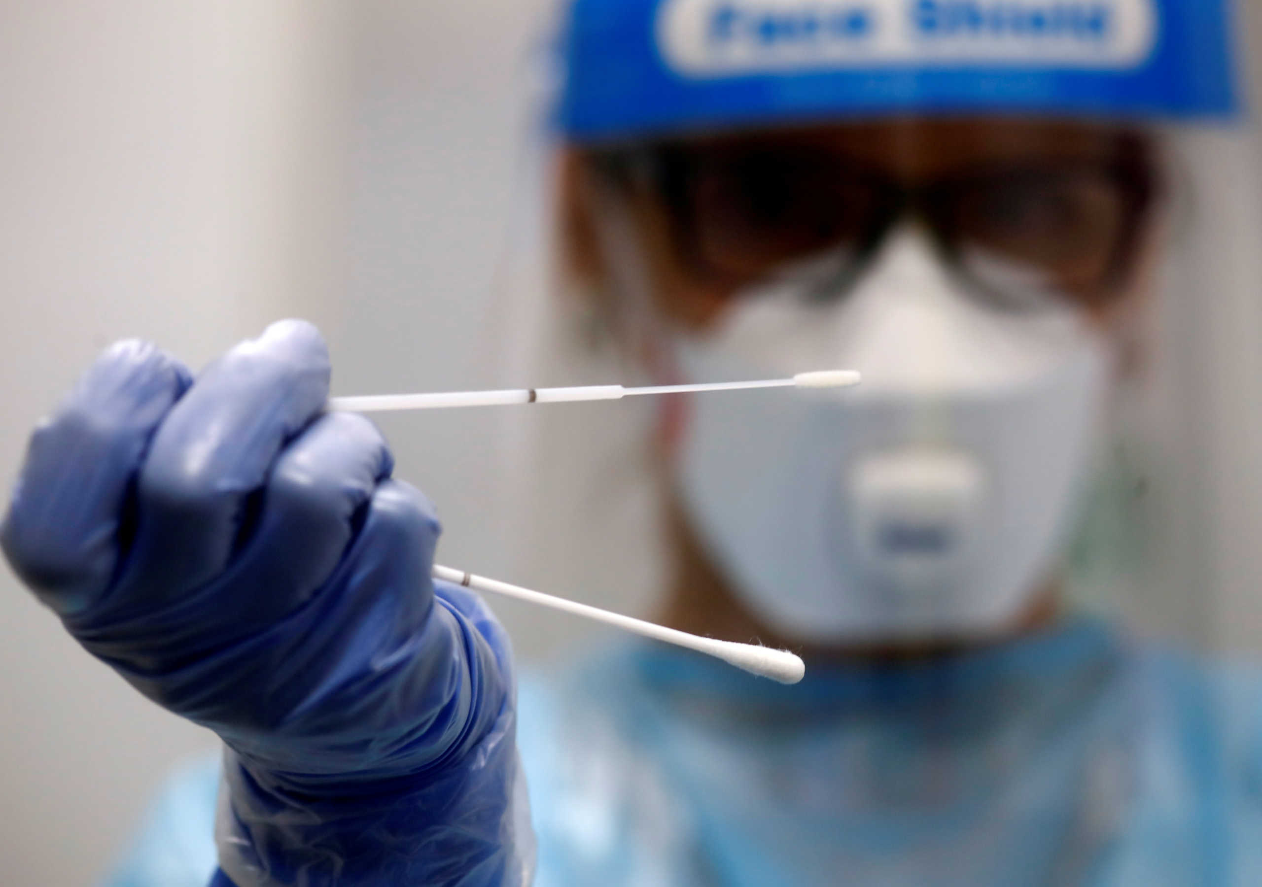 FILE PHOTO: A retired doctor who volunteered to work at the new Duesseldorf Airport Corona Test Centre holds a test stick before a voluntary coronavirus disease (COVID-19) test at the new Duesseldorf Airport Corona Test Centre in Duesseldorf, Germany, July 27, 2020. REUTERS