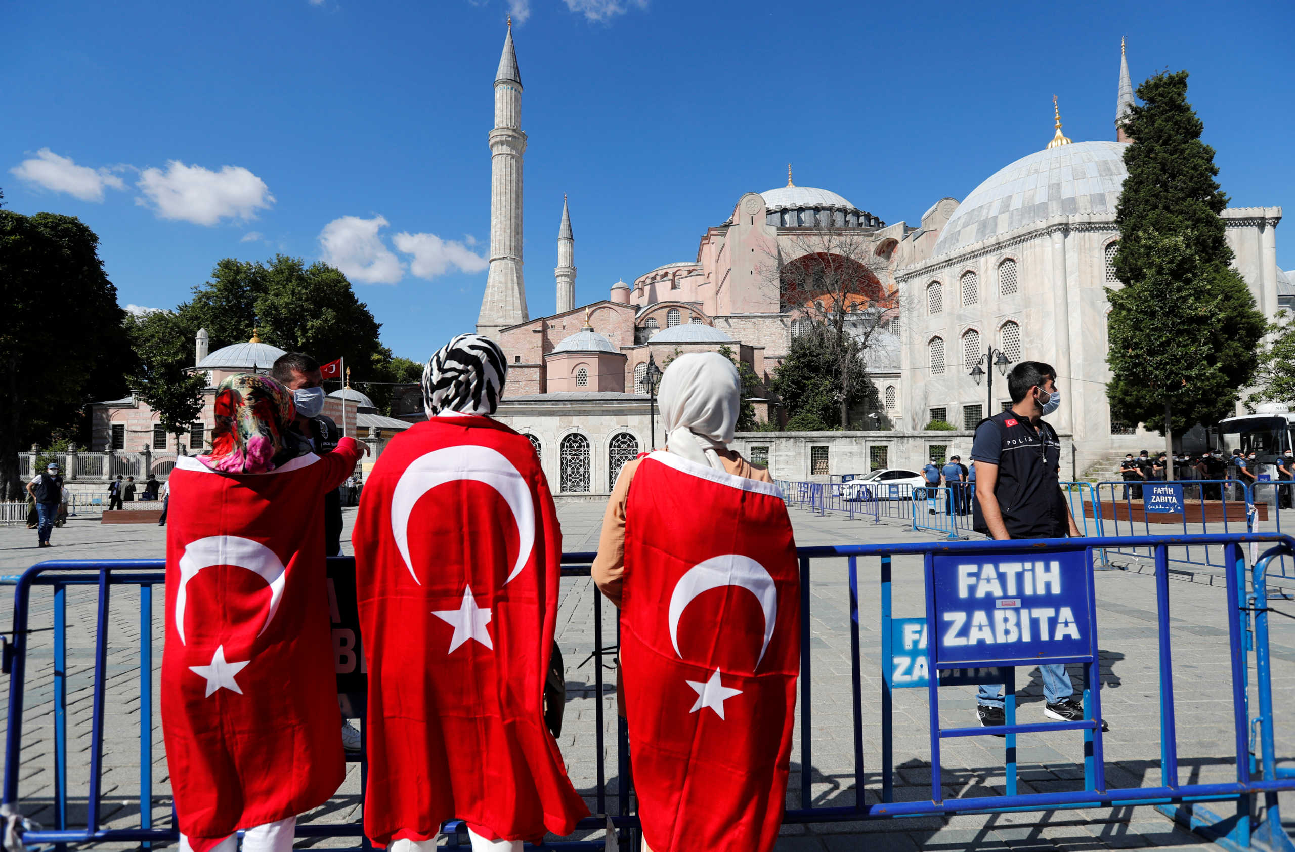 People wear Turkish flags in front of Hagia Sophia or Ayasofya, after a court decision that paves the way for it to be converted from a museum back into a mosque, in Istanbul, Turkey, July 10, 2020. REUTERS