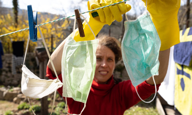 Worried Mature Adult Woman Hanging Face Masks on Clothesline in Back Yard