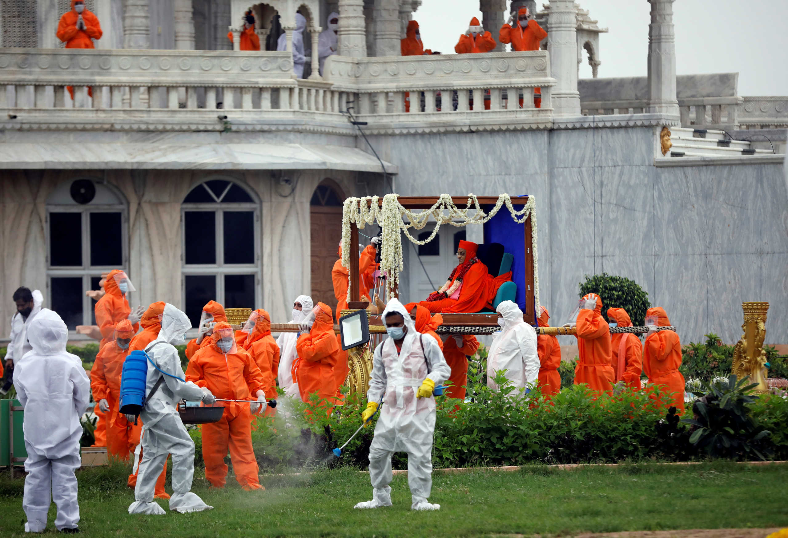 SENSITIVE MATERIAL. THIS IMAGE MAY OFFEND OR DISTURB    Healthcare workers spray sanitizer as devotees wearing personal protective equipment carry the body of Purushottampriyadasji Swamishree Maharaj, head priest of Maninagar Shree Swaminarayan Gadi Sansthan, who died due to the coronavirus disease (COVID-19), for his last rites at Smruti Temple premises in Ahmedabad, India, July 16, 2020. REUTERS
